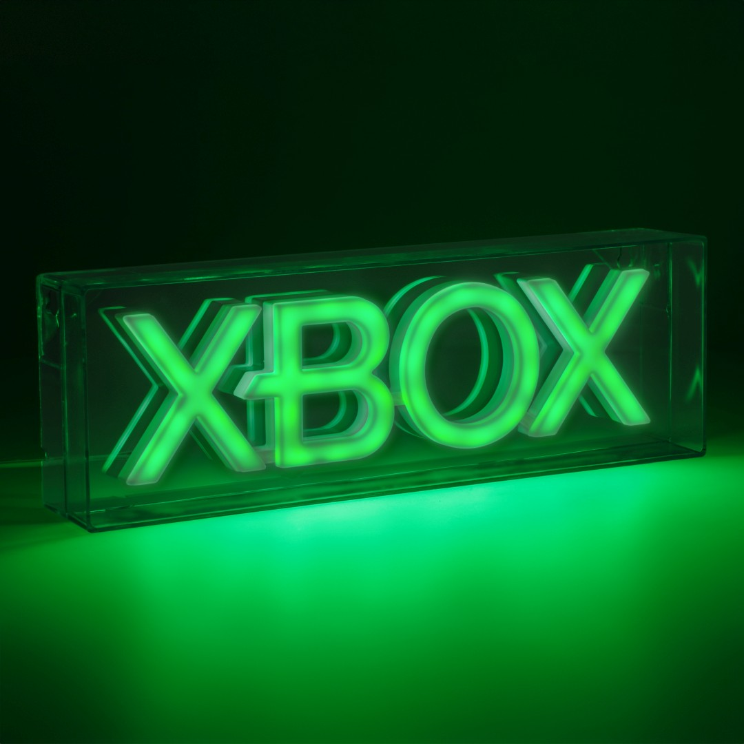 Podświetlone logo Xbox w przezroczystej obudowie na zielonym podłożu.
