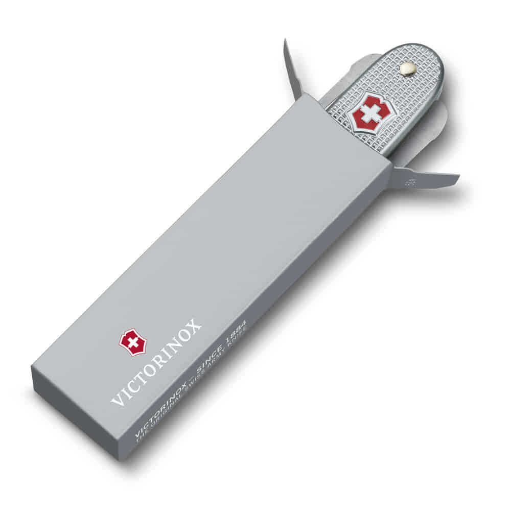 Beyaz haçlı gümüş Victorinox çakı gri bir kutunun içinde kısmen duruyor.