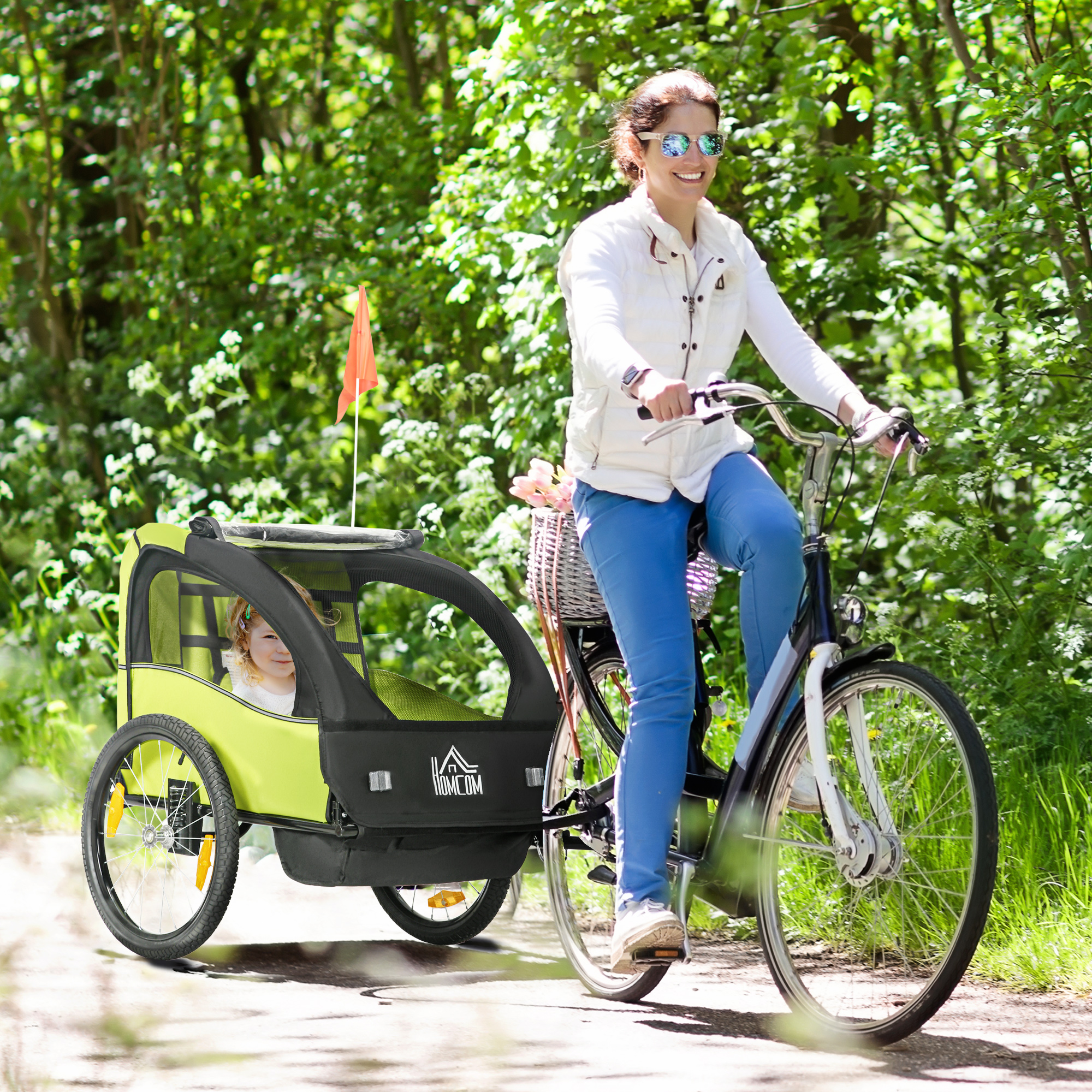 Mujer monta en bicicleta con remolque infantil en el bosque.