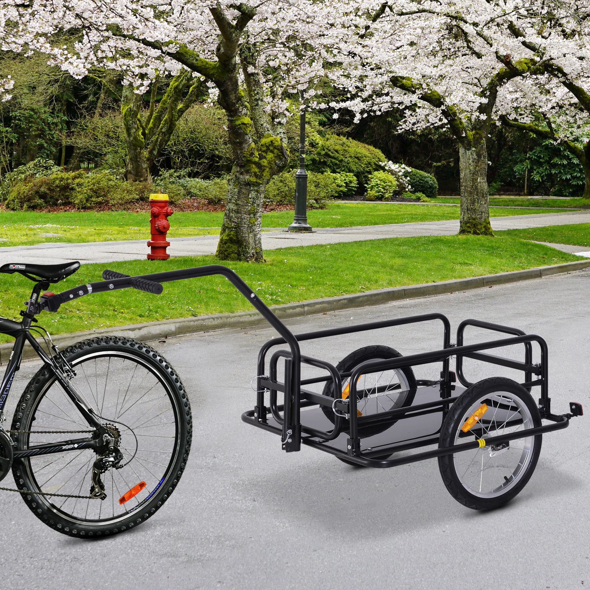 Bicicleta con remolque negro en carretera asfaltada, con cerezos en flor de fondo.