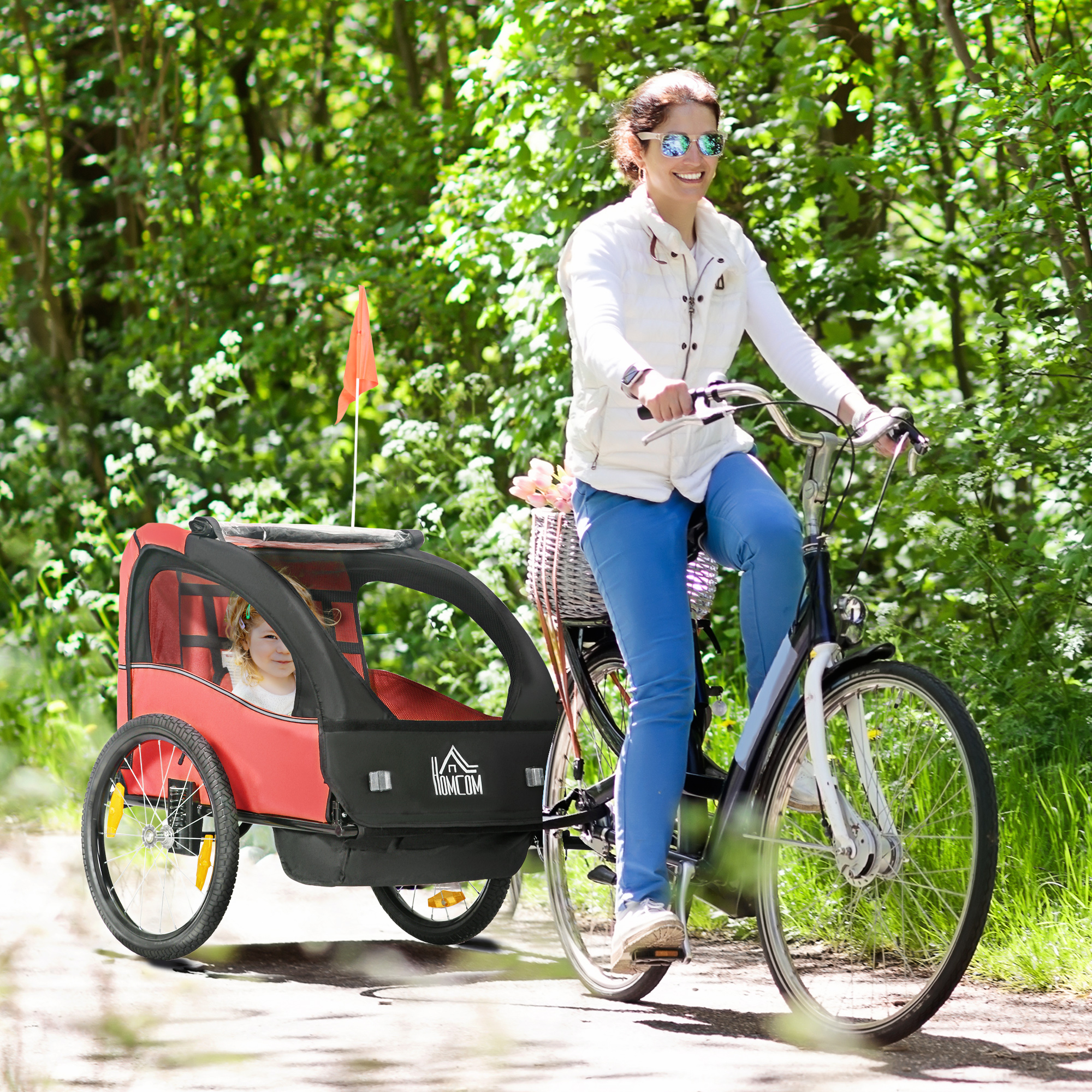 Una mujer monta en bicicleta con un remolque infantil en el bosque.