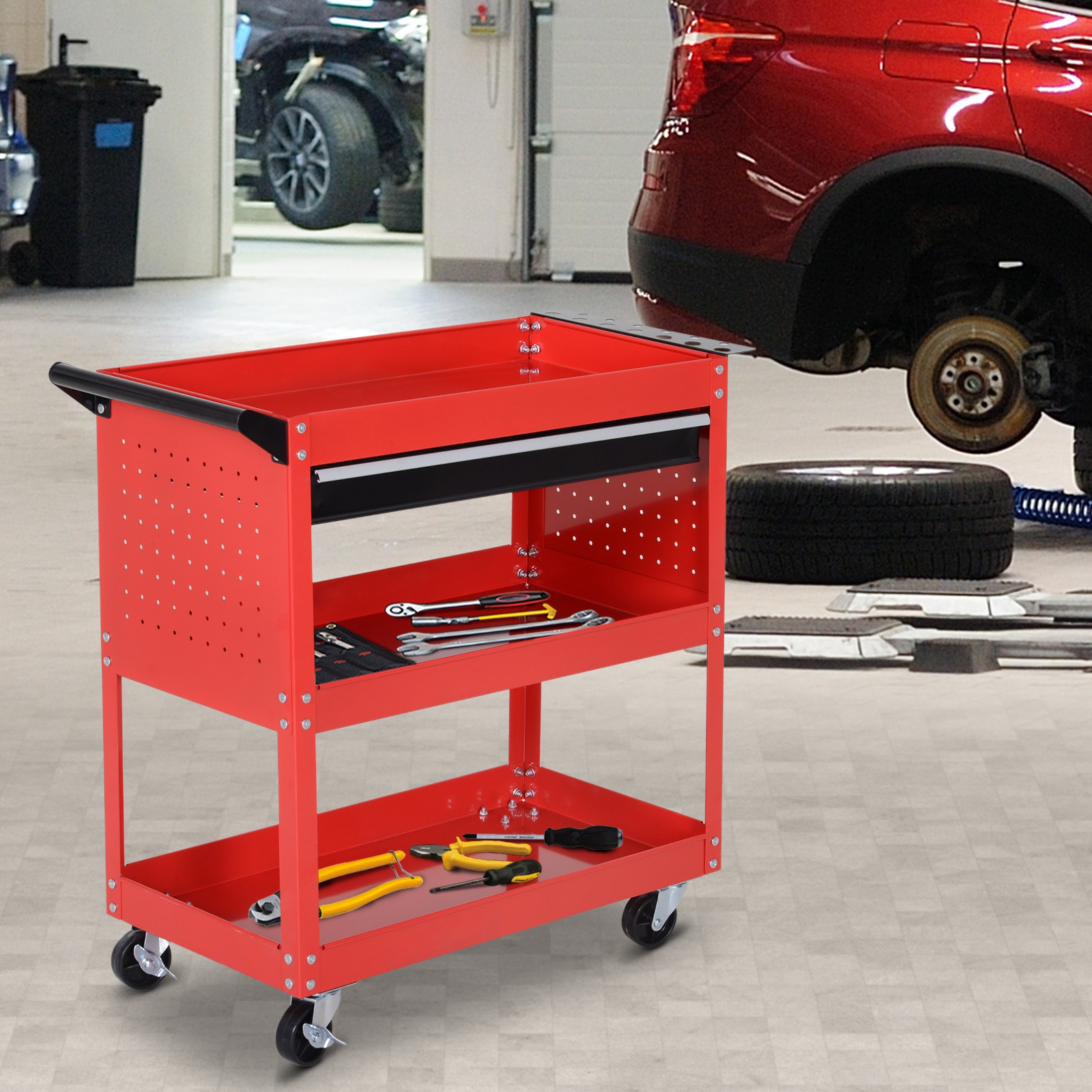 Carro de herramientas rojo con herramientas y coches en un taller.