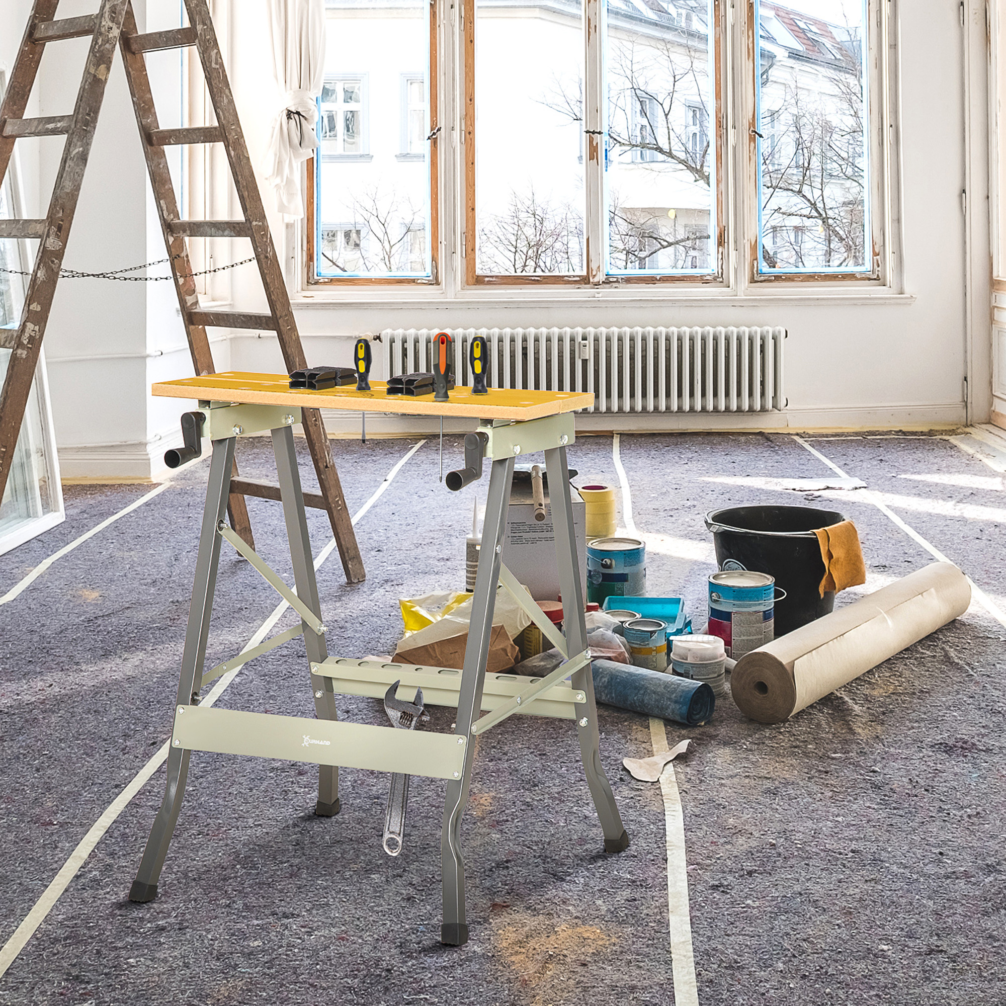 Banco de trabajo con herramientas, escaleras y latas de pintura en una habitación en renovación.