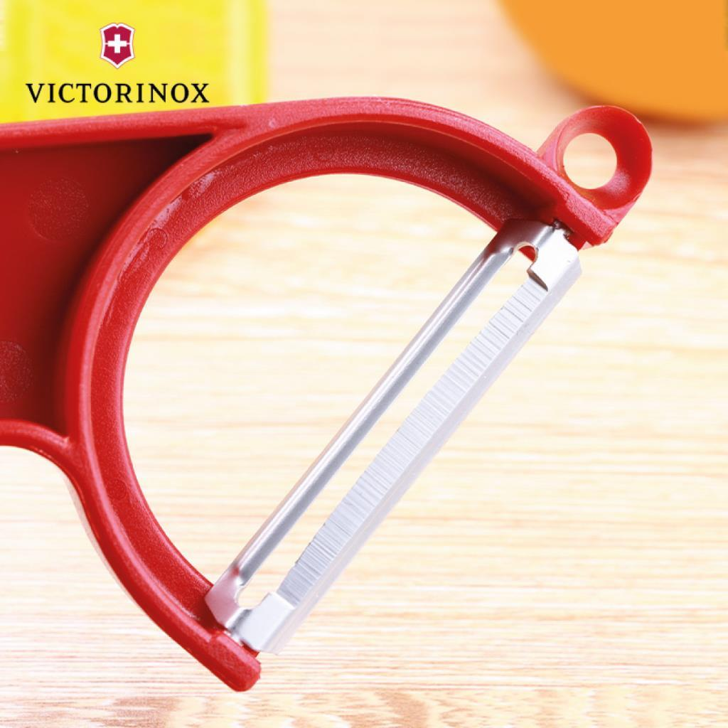 Ahşap zeminde metal bıçaklı kırmızı Victorinox soyucu.