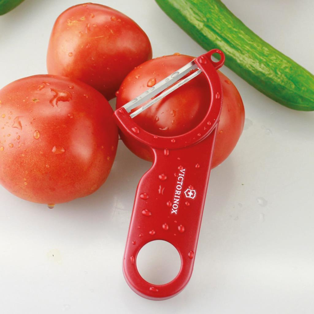 Kırmızı bir Victorinox soyacak domateslerin üzerinde duruyor, arkada salatalık var.