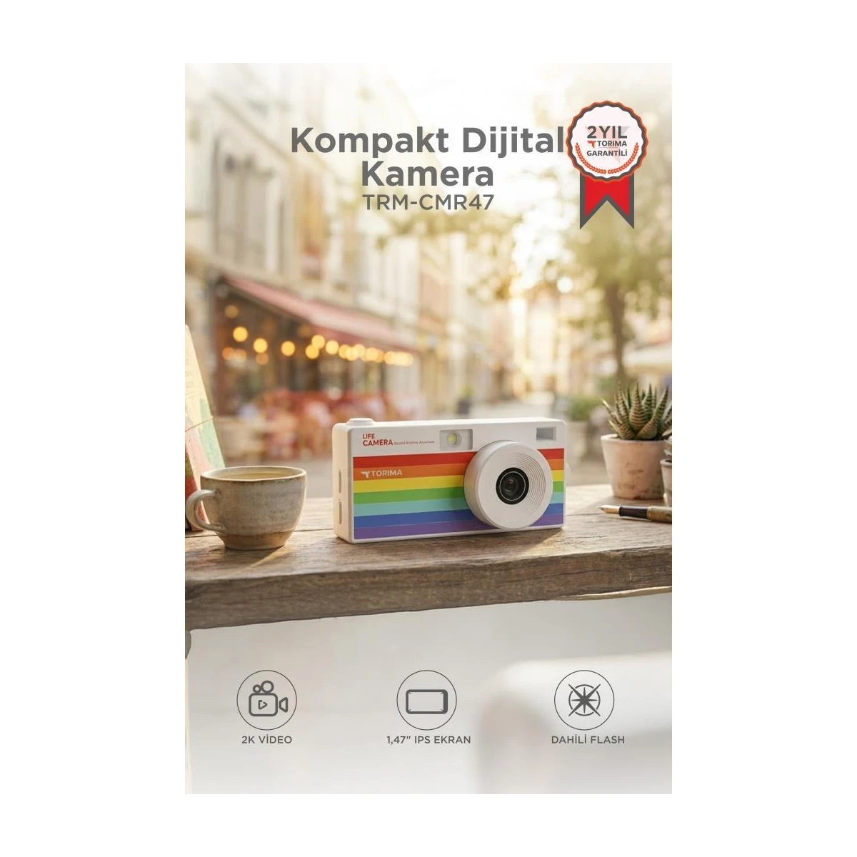 Gökkuşağı şeritli kompakt dijital kamera, fincan ve bitki yanında.