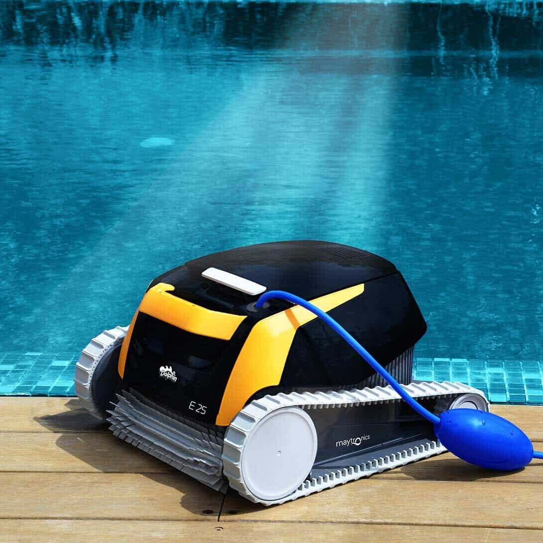 Un limpiafondos negro y amarillo con cable azul sobre madera junto a la piscina.