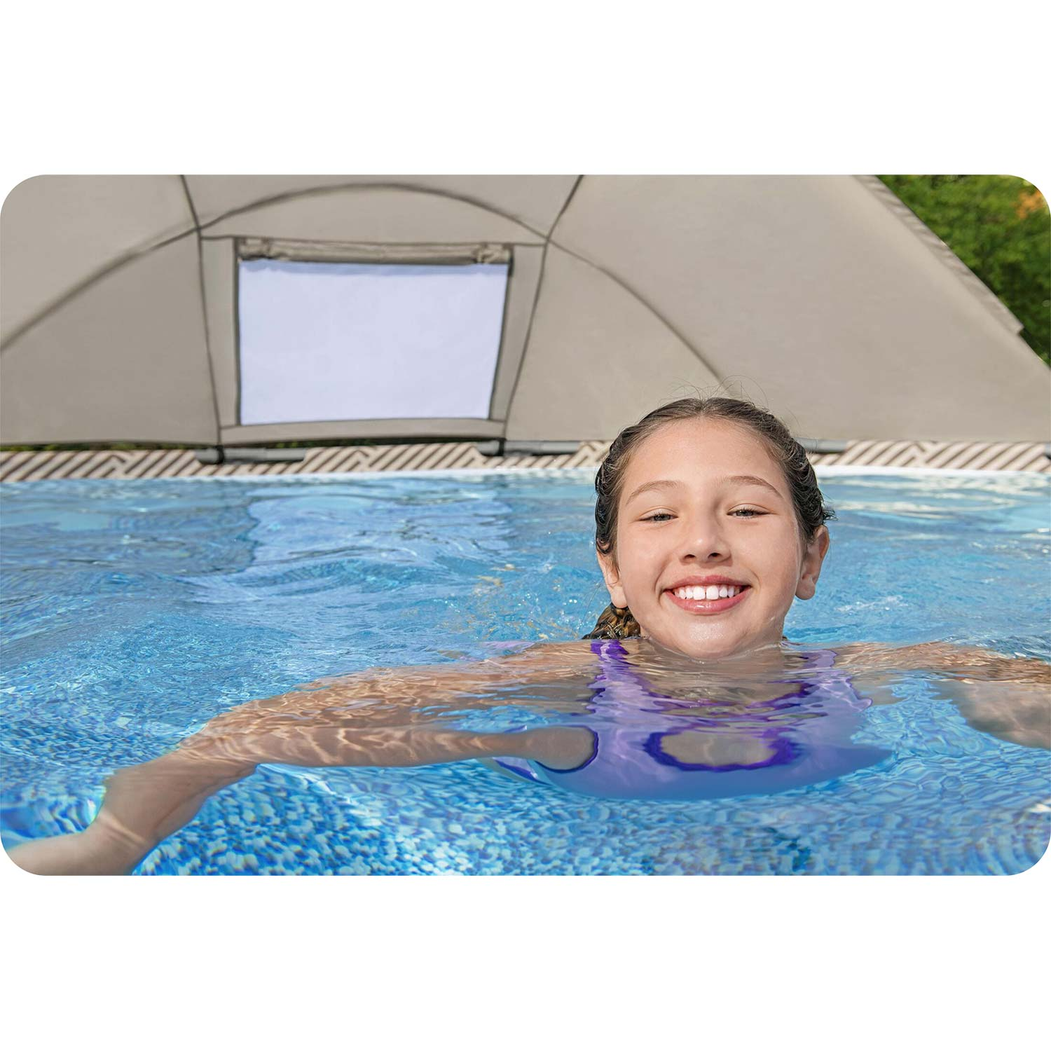 Ein lachendes Mädchen schwimmt in einem Pool unter einem Poolzelt.