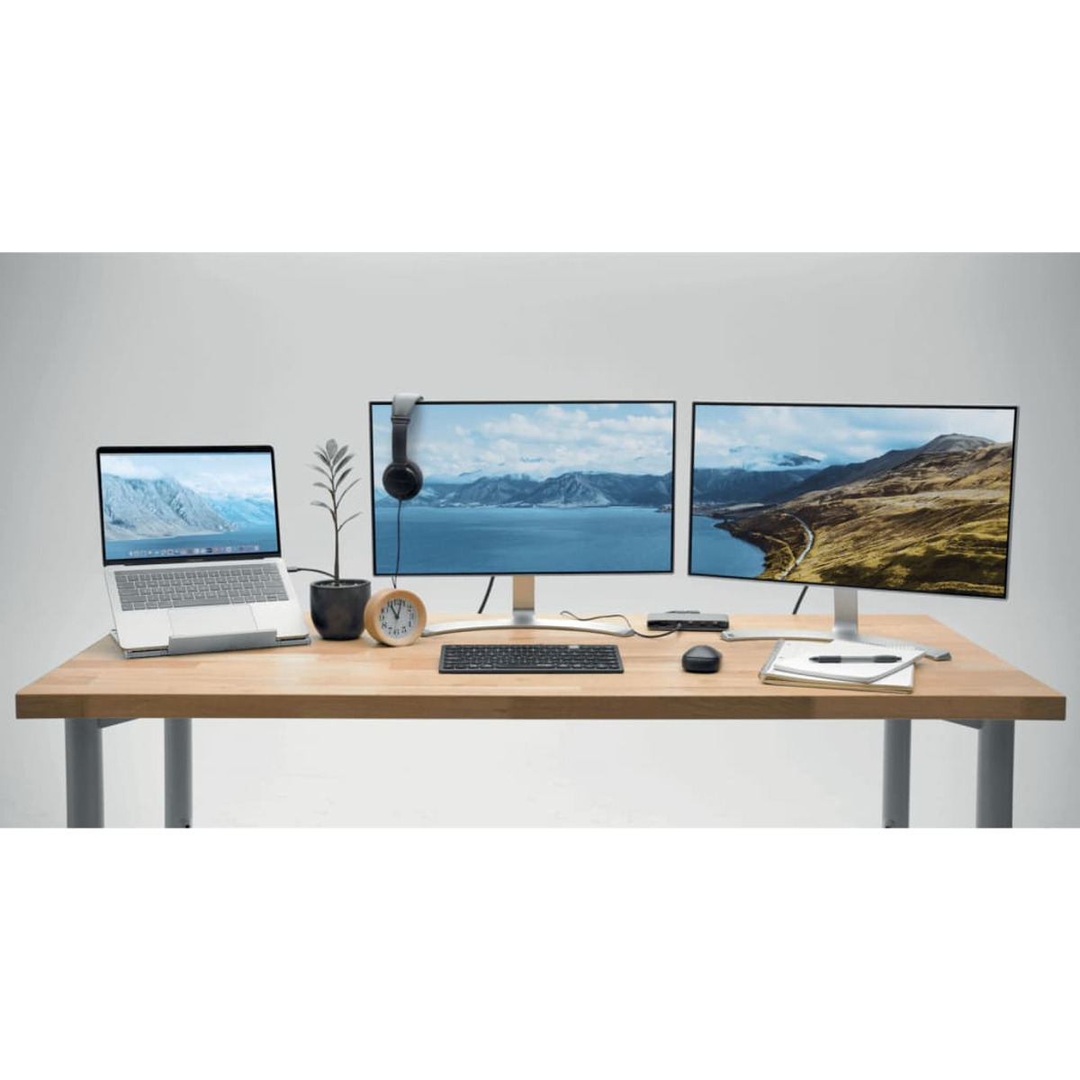 A desk with a laptop, two monitors, a keyboard, mouse, and headphones.