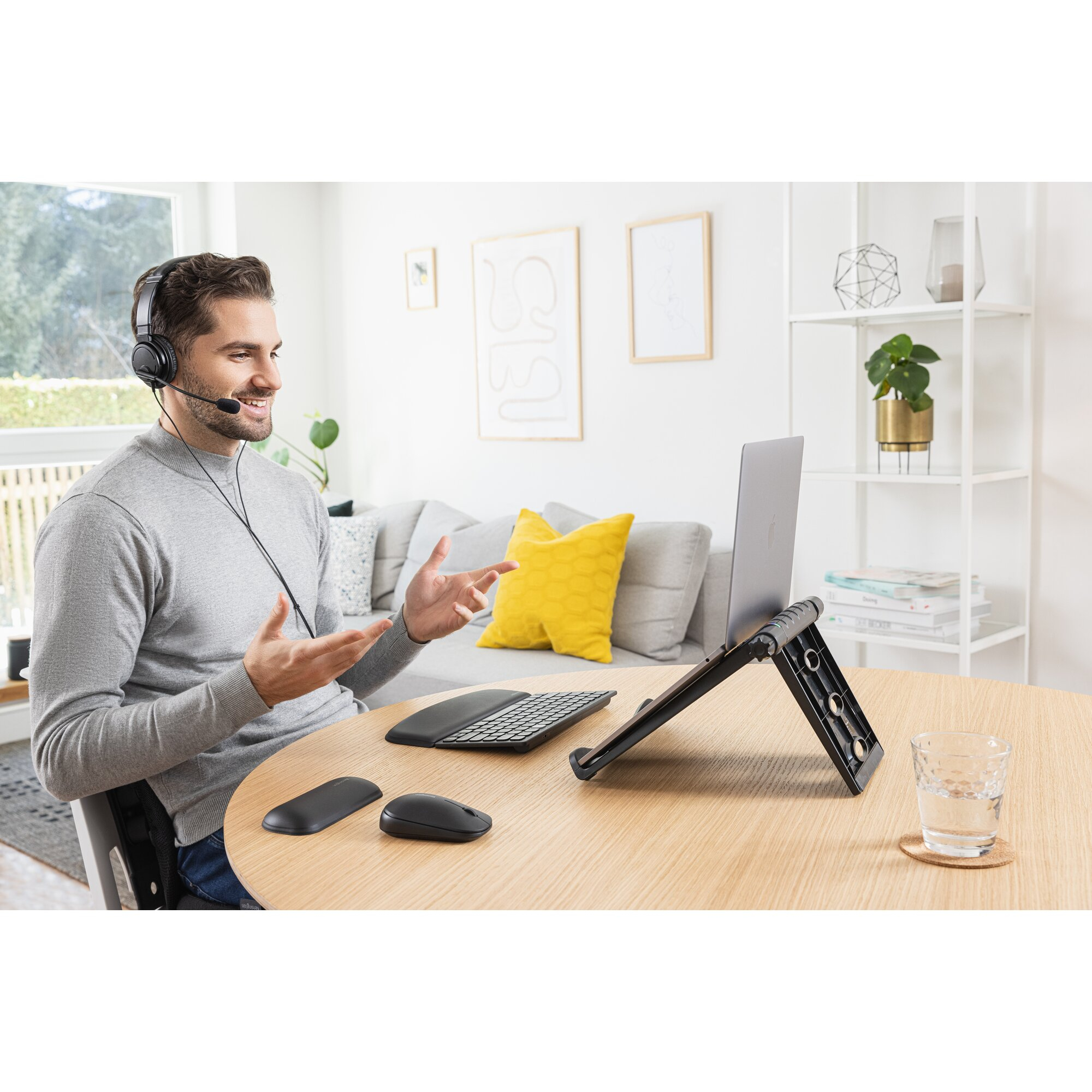 Man wearing headset at desk, talking to laptop. Mouse and keyboard are nearby.