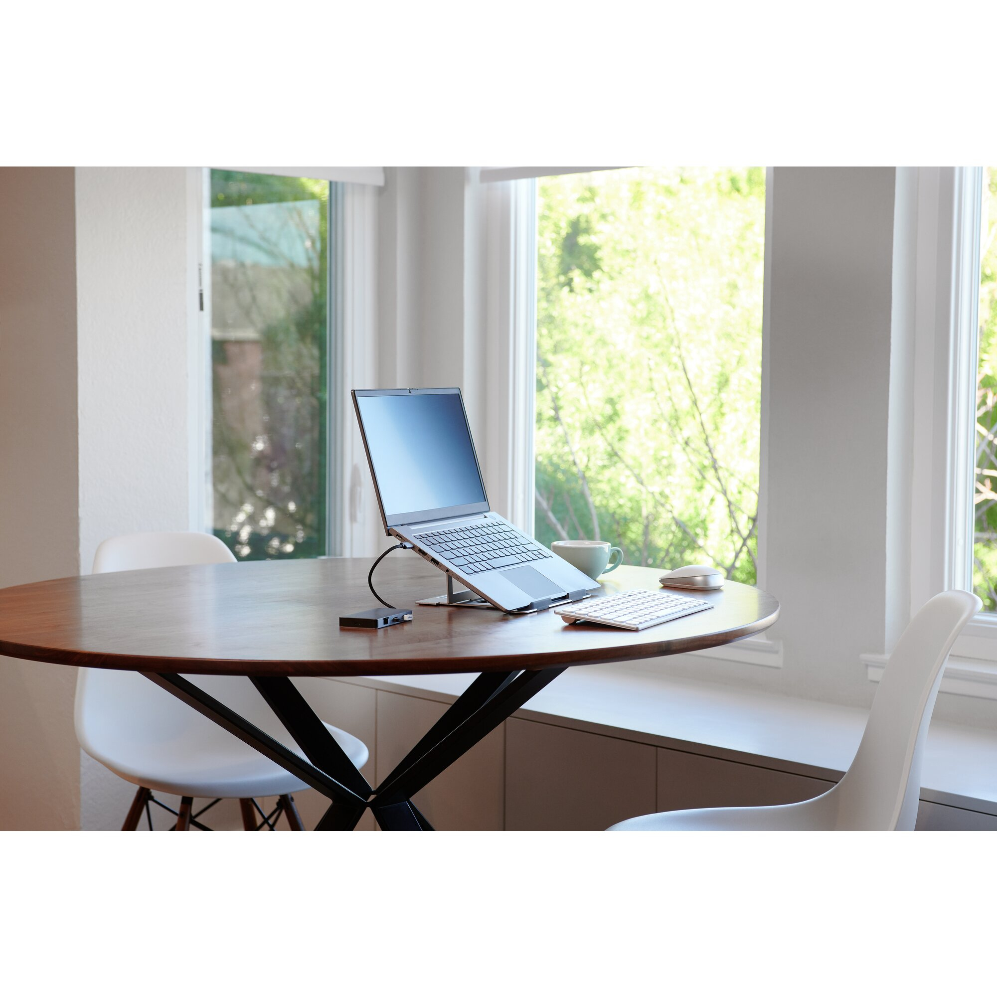 Un ordinateur portable sur un support avec clavier et souris sur une table en bois.