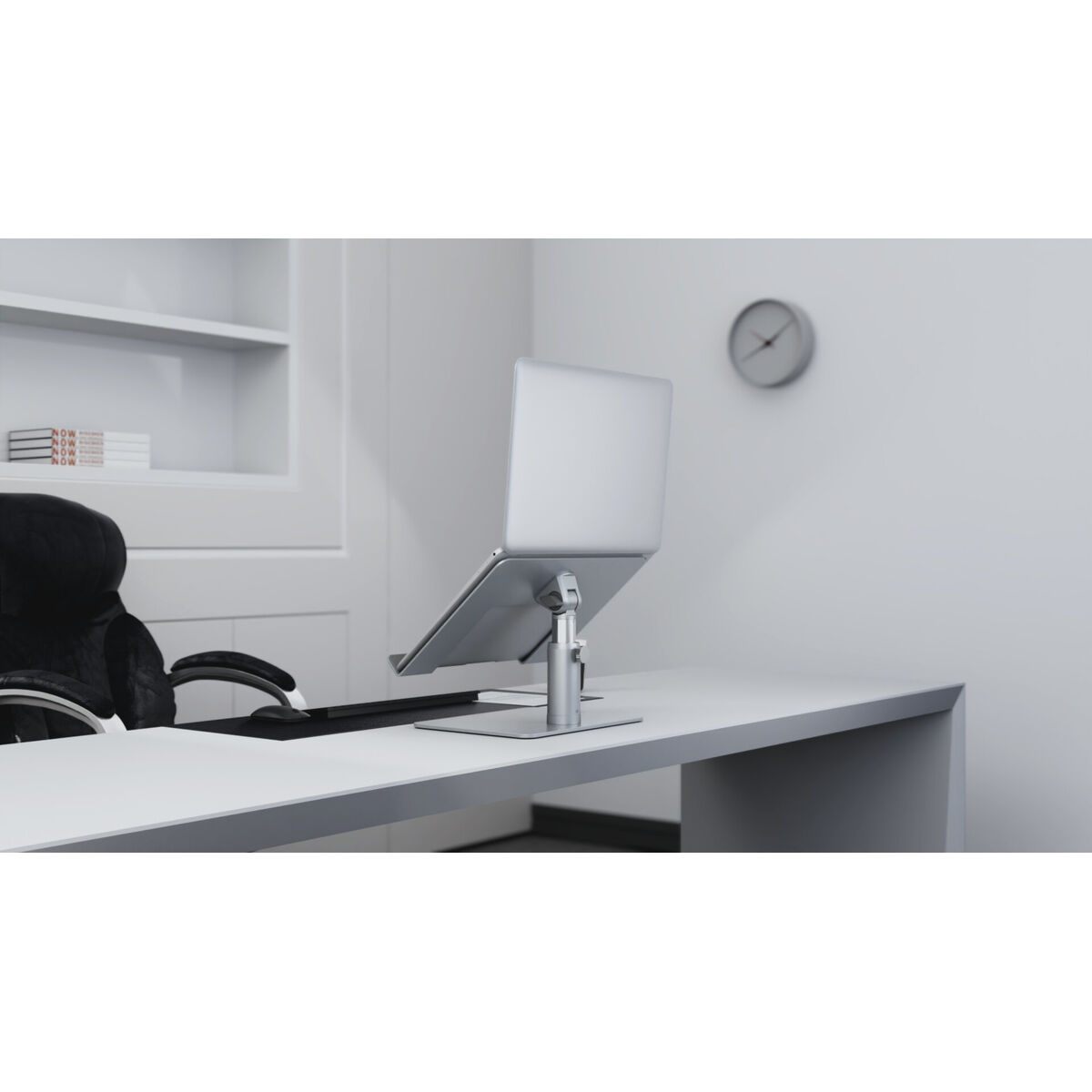 A silver laptop is on a laptop stand on a white desk.