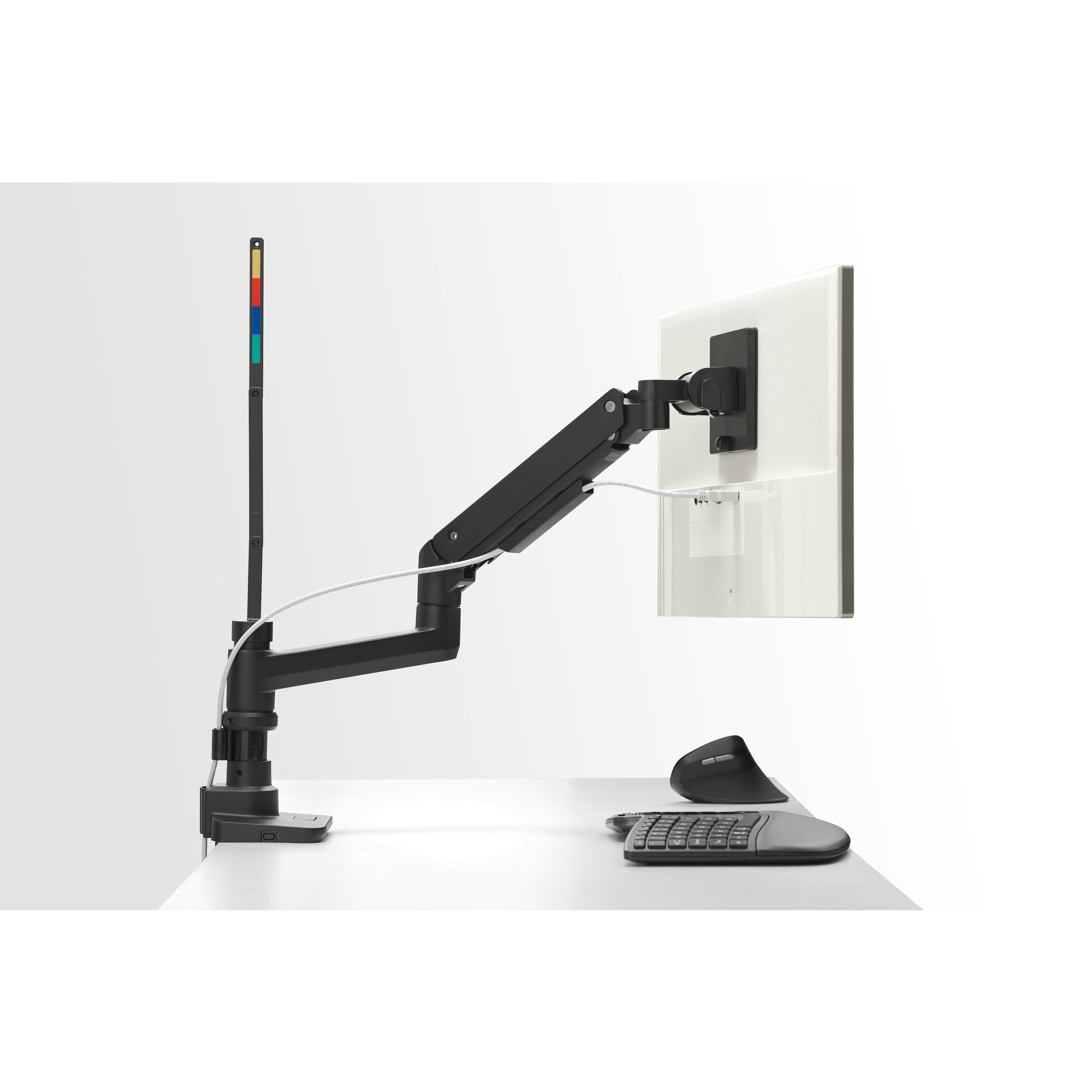 Un bras de moniteur noir tient un moniteur blanc au-dessus d'un clavier et d'une souris.