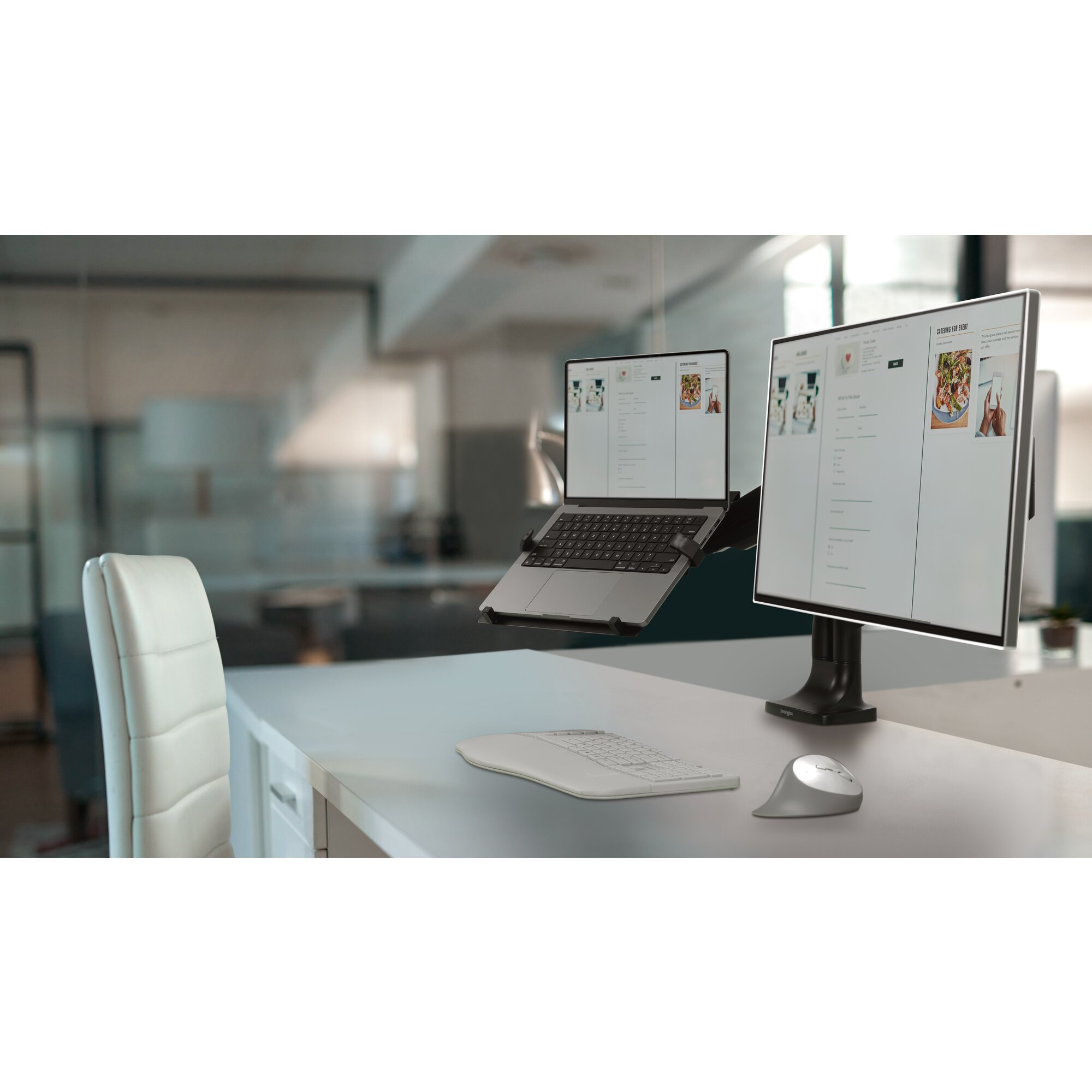 A modern office setup with a laptop, vertical monitor, keyboard, and mouse.