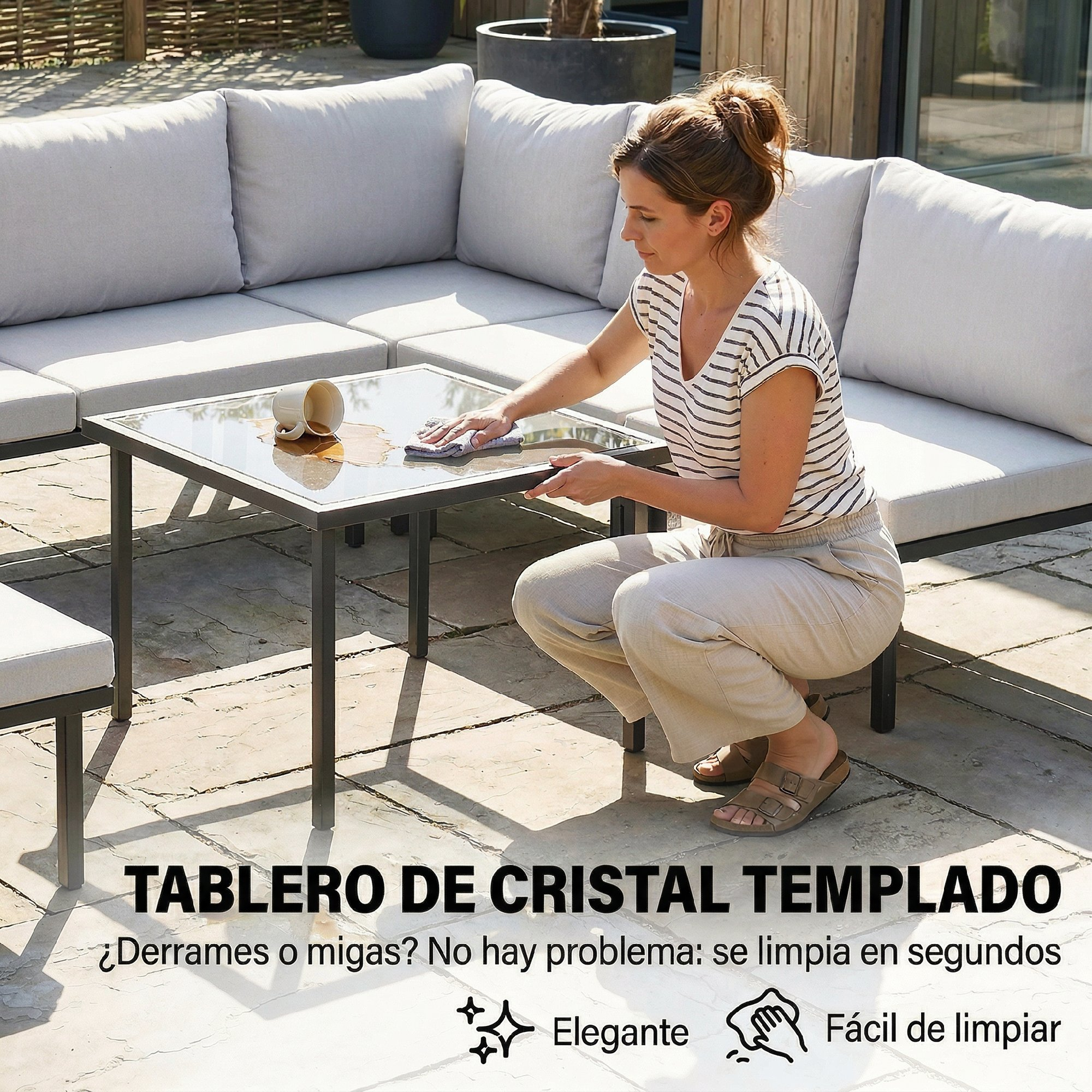 Una mujer limpia un derrame de una taza sobre una mesa de cristal.