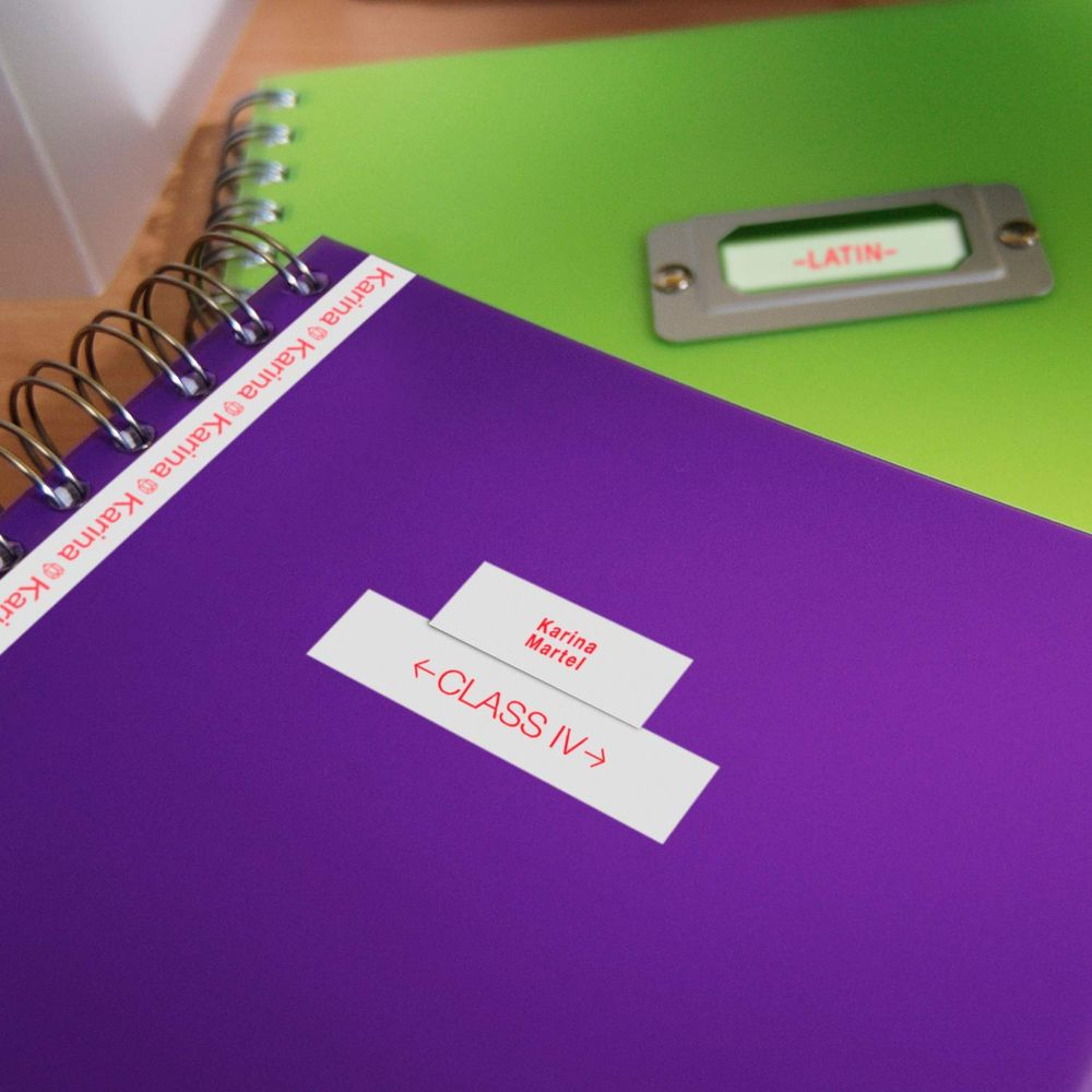 Lila und grüne Notizbücher mit Namens- und Klassenaufklebern.