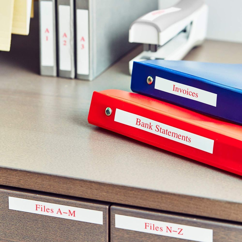 Ordner mit Rechnungen und Kontoauszügen auf einem Schreibtisch. Stapler im Hintergrund.