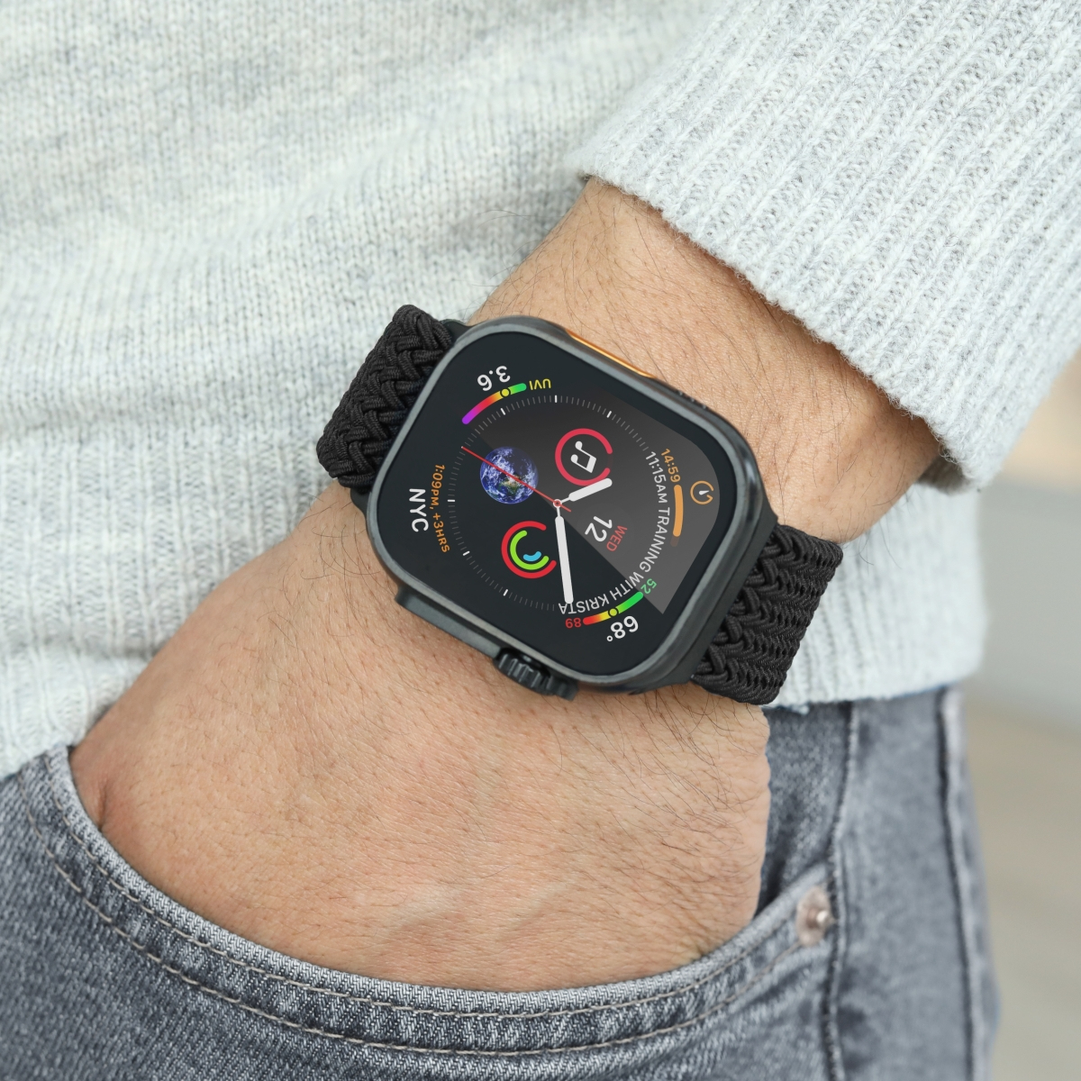 Maglione grigio, jeans e uno smartwatch con cinturino nero al polso.