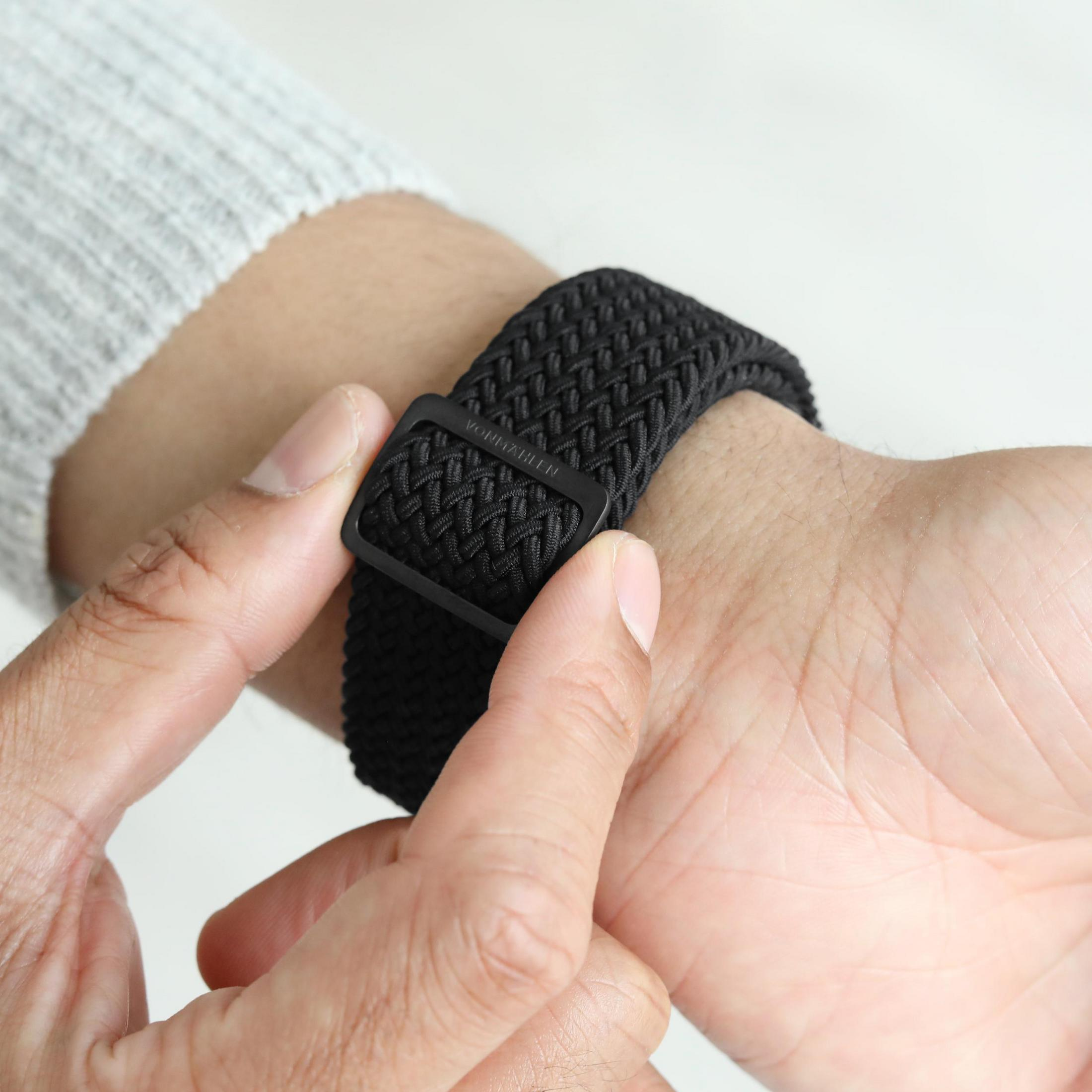 Cinturino orologio in tessuto nero con fibbia in metallo nero regolato su polso.