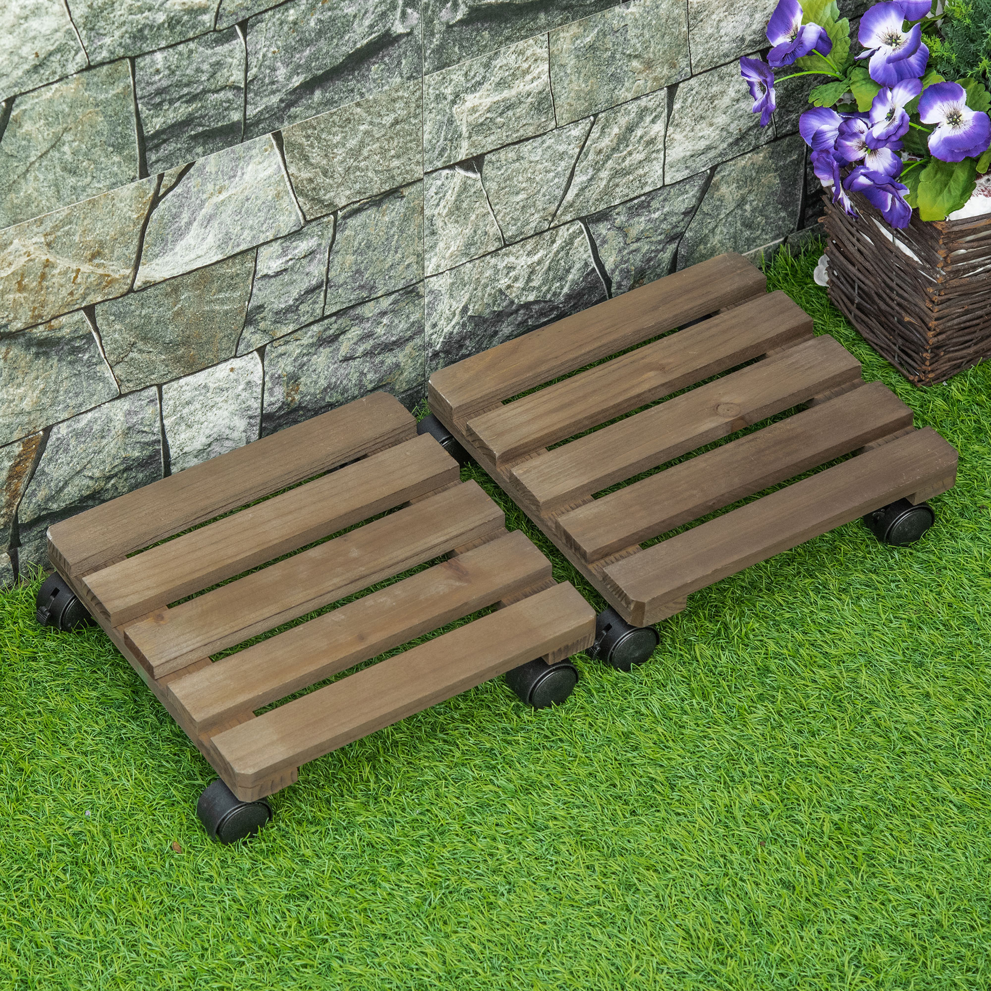 Dos soportes de madera con ruedas sobre césped artificial, frente a una pared de piedra.