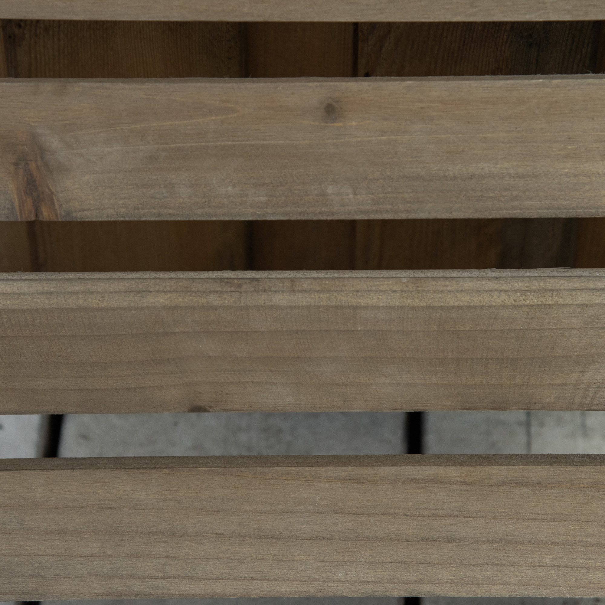 Listones de madera de una caja de madera con suelo gris al fondo.