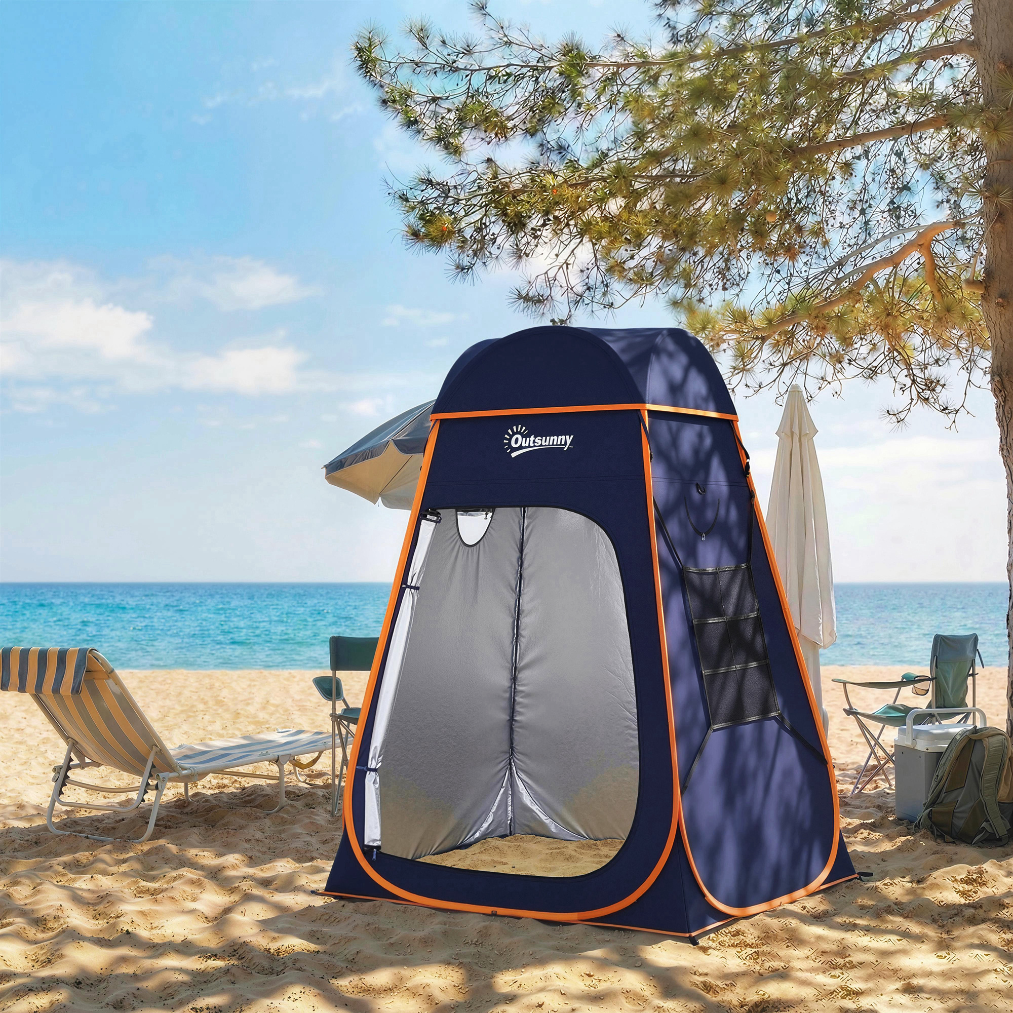 Una carpa de playa azul marino con ribetes naranjas se encuentra en la arena junto a una tumbona.