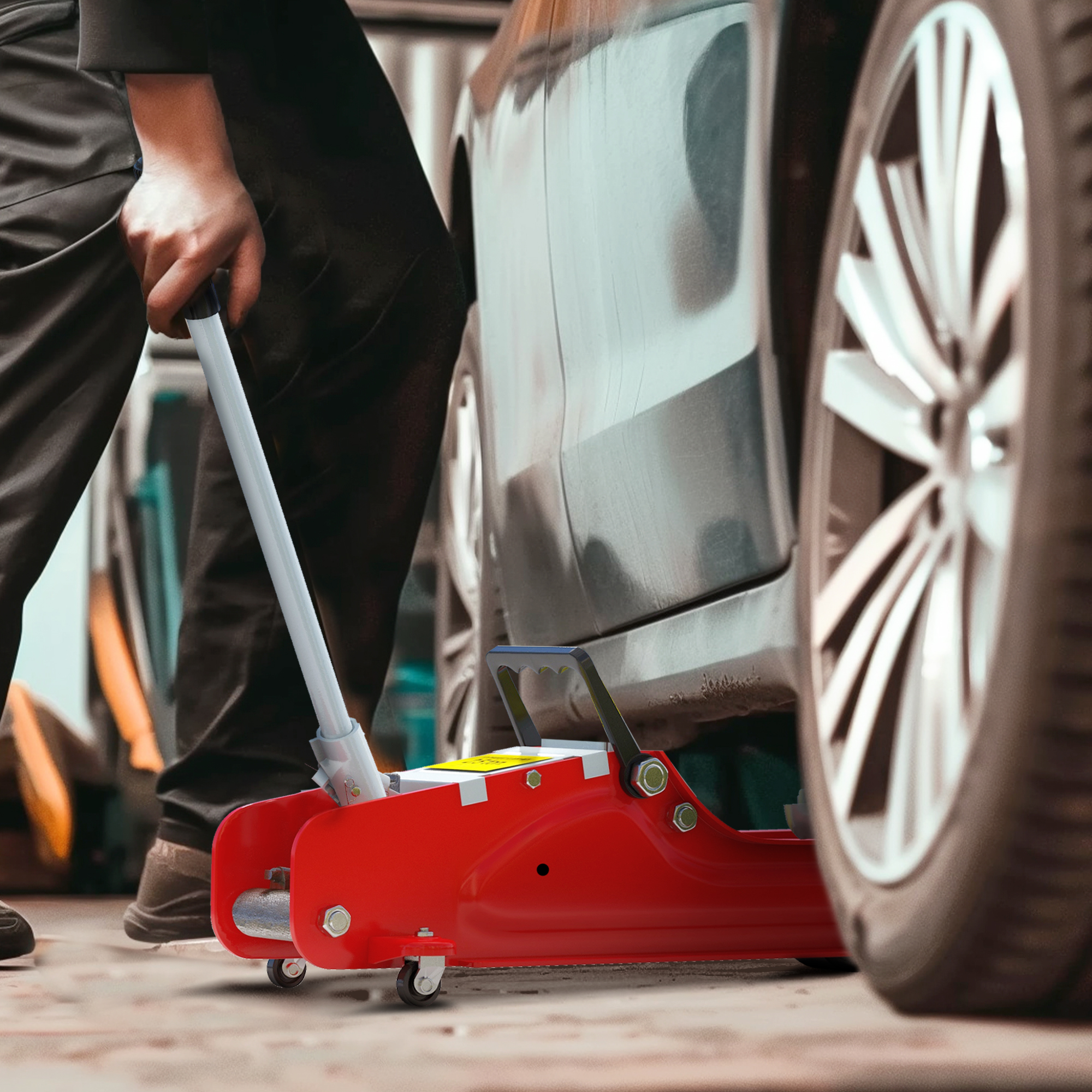 Un hombre opera un gato hidráulico rojo junto a un coche con llantas plateadas.
