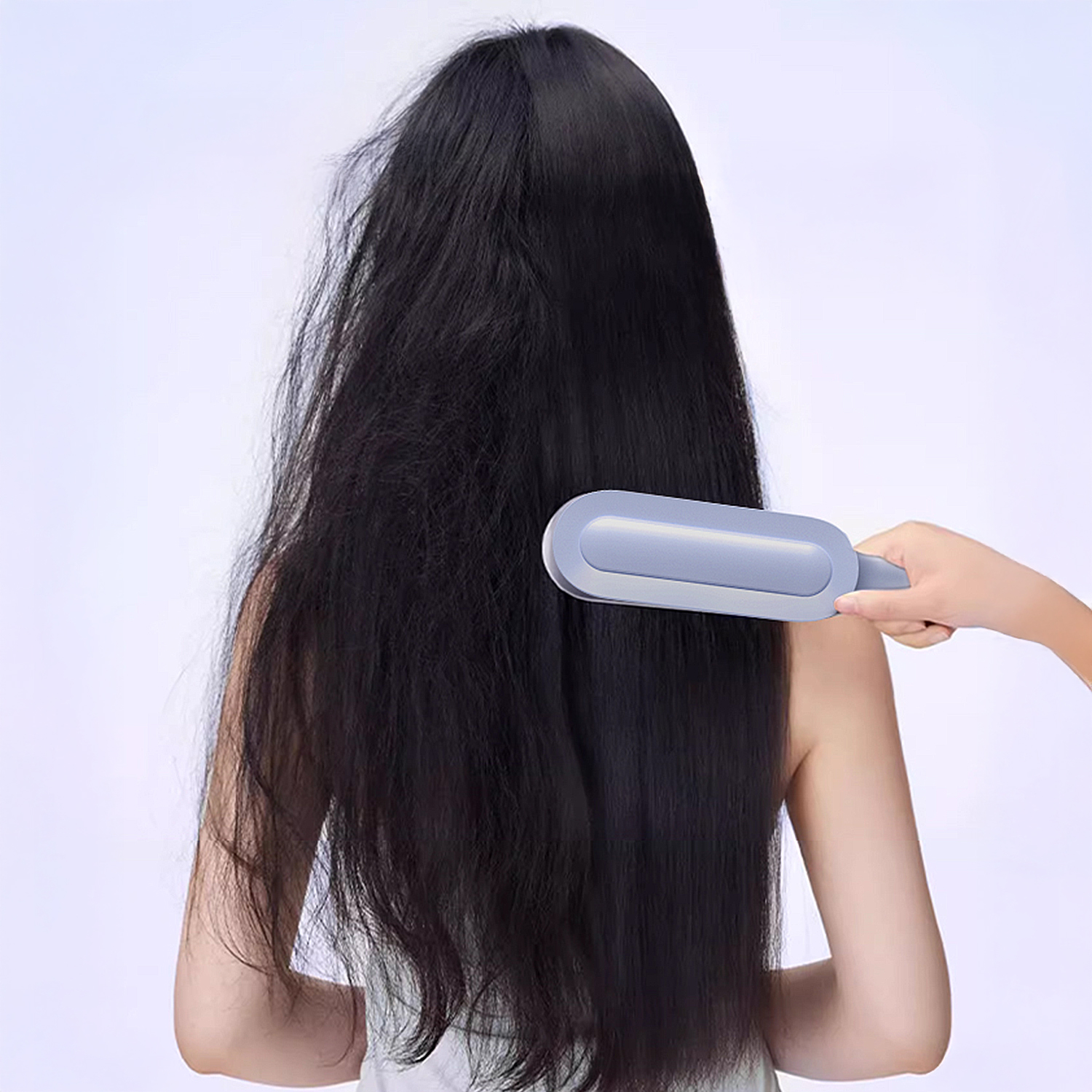 Una mano spazzola capelli lunghi e scuri con una spazzola blu.