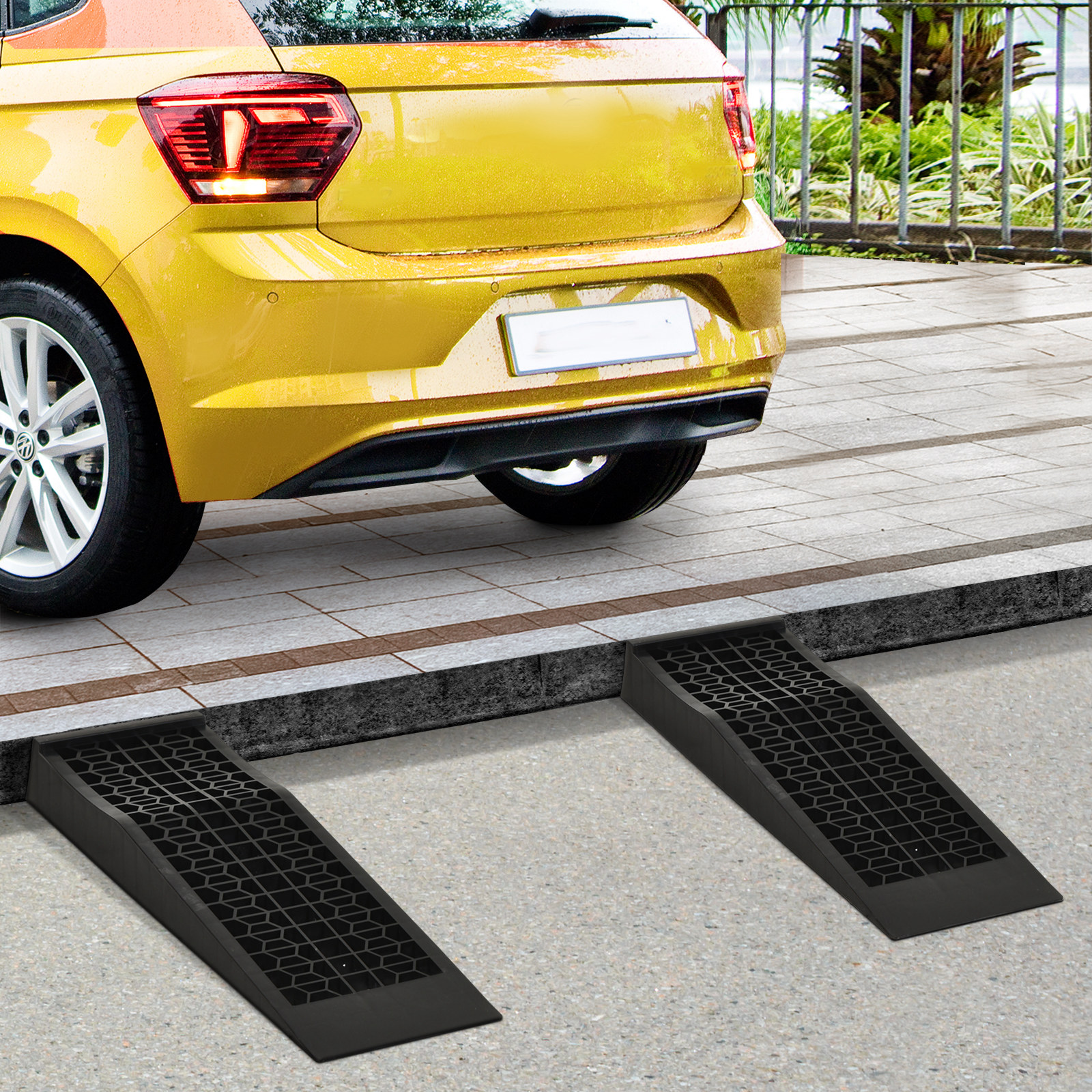 Coche amarillo aparcado ante dos rampas negras sobre superficie pavimentada.