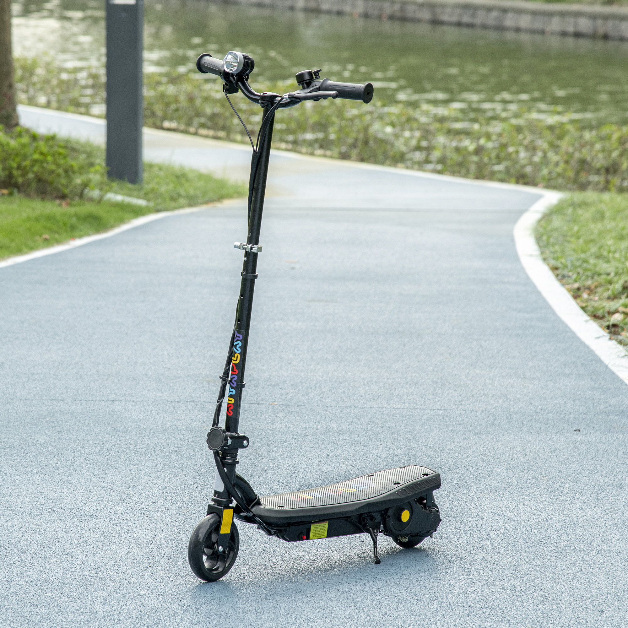 Un patinete eléctrico negro está aparcado en un camino azul junto a un estanque.