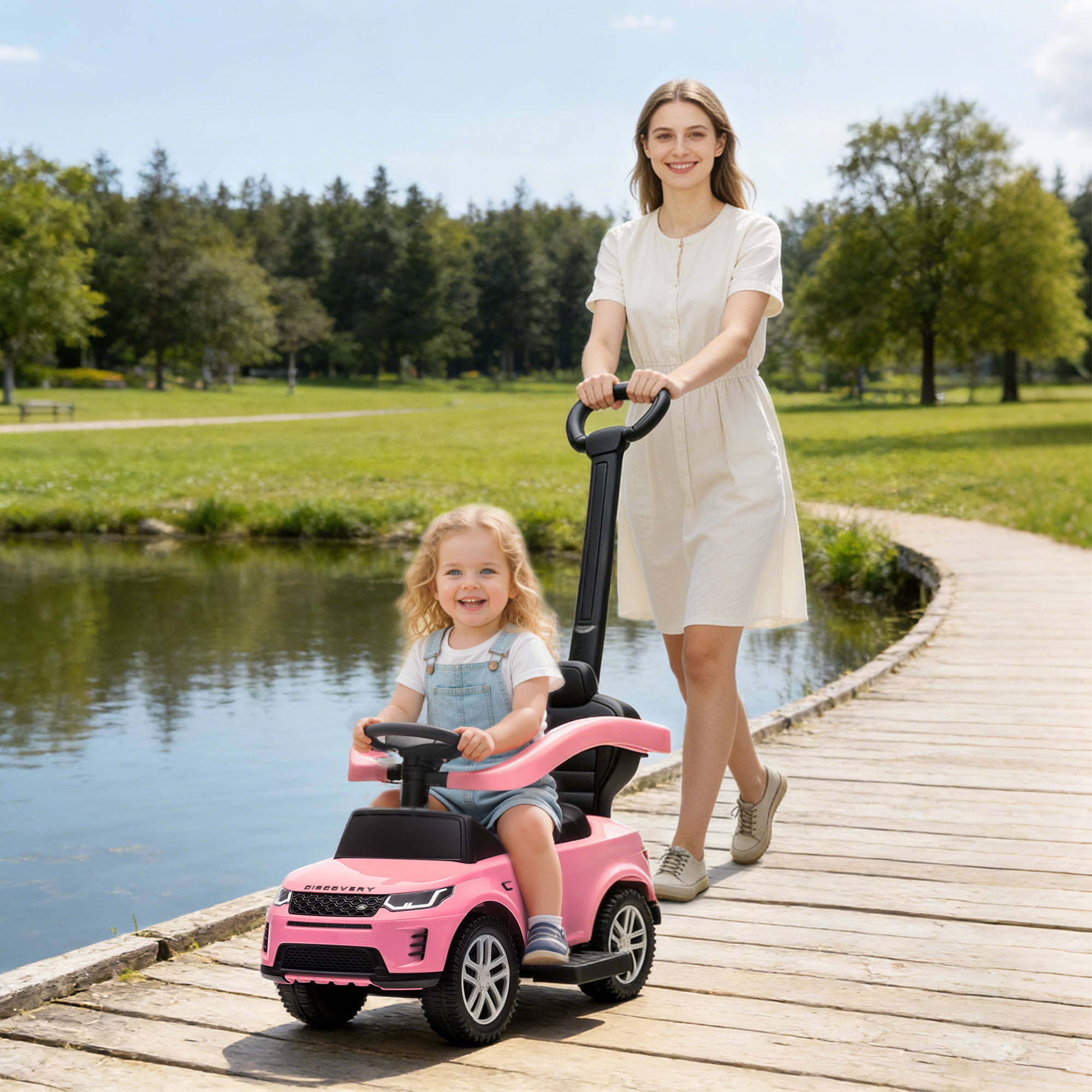 Mujer empuja coche de juguete rosa con niño en sendero de madera.