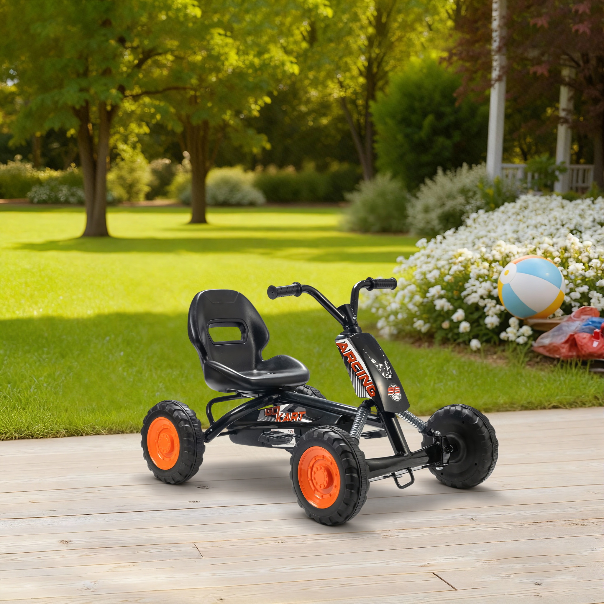 Un go-kart negro con ruedas naranjas está en una terraza de madera. Hay una pelota cerca.