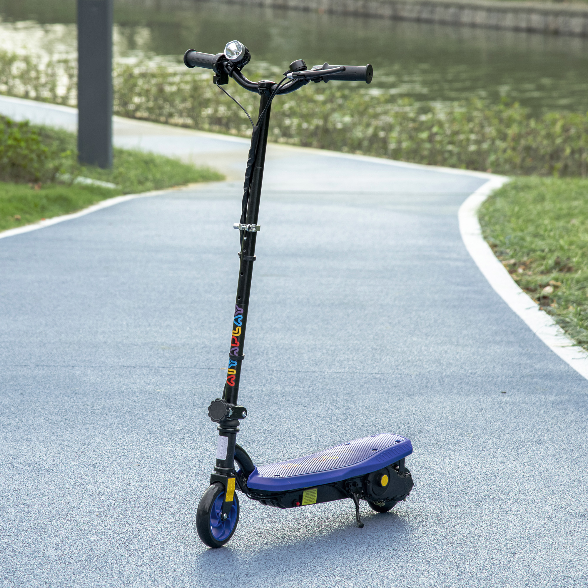 Un patinete negro con plataforma azul está en un camino azul junto al agua.