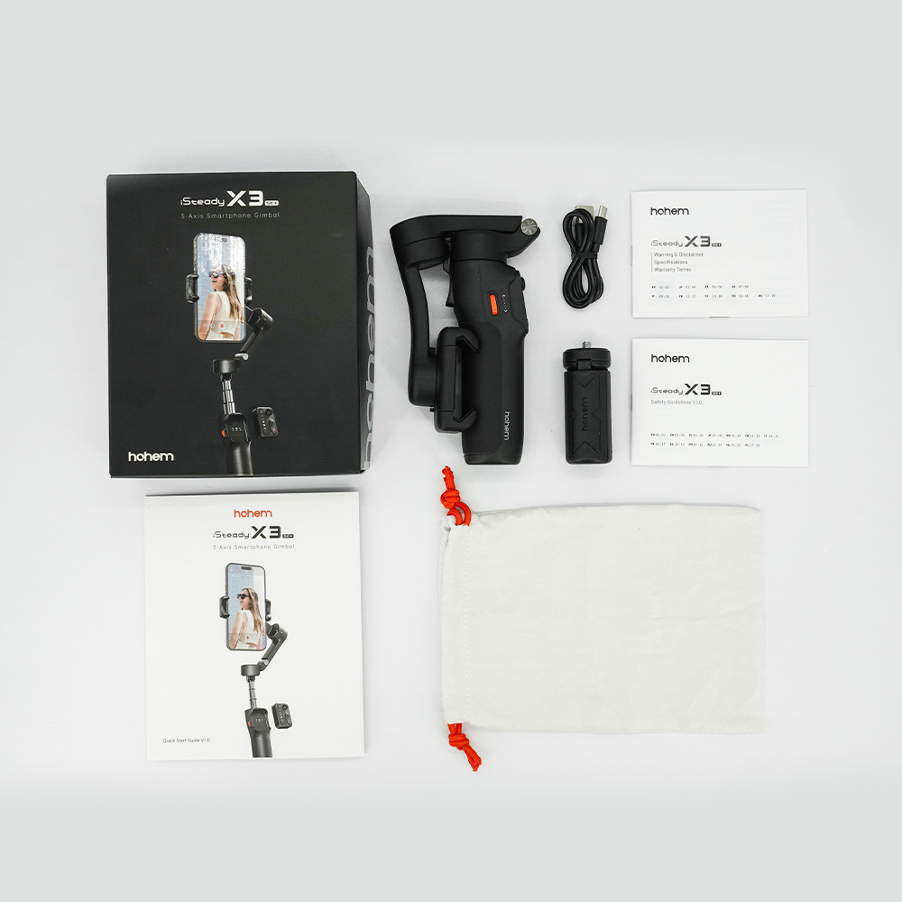 Un gimbal Hohem, cable de carga, manuales y bolsa de tela sobre superficie blanca.