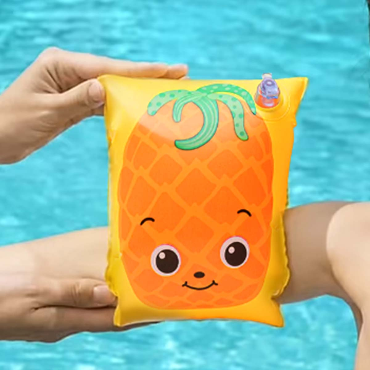 Bracciolo giallo con faccia di ananas, indossato su un braccio in acqua.