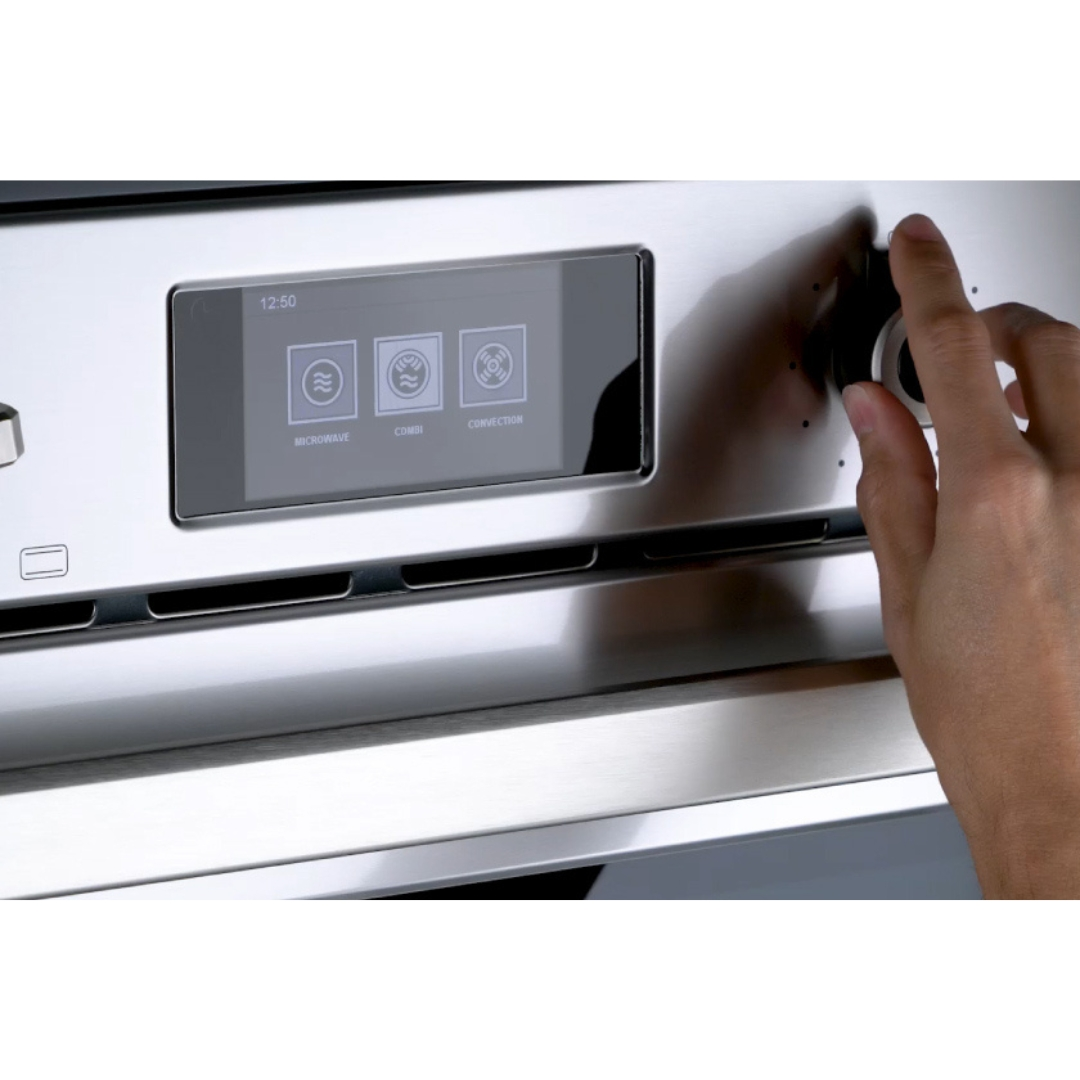 Una mano gira una manopola su un forno in acciaio inox con display touch.