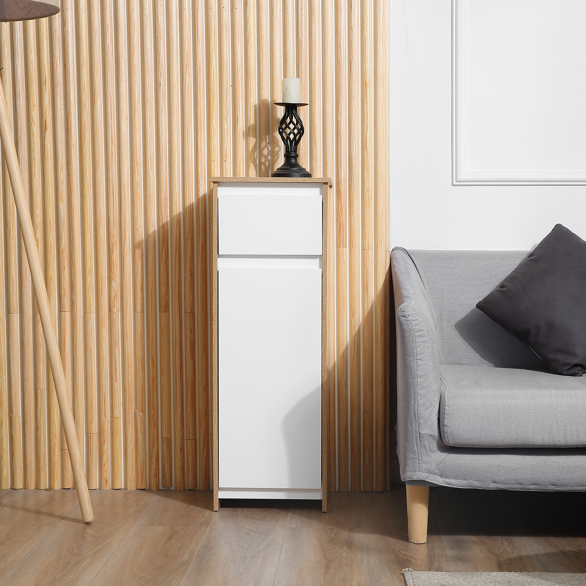 Un mueble blanco alto y delgado está contra una pared de madera acanalada. Un candelabro con vela.