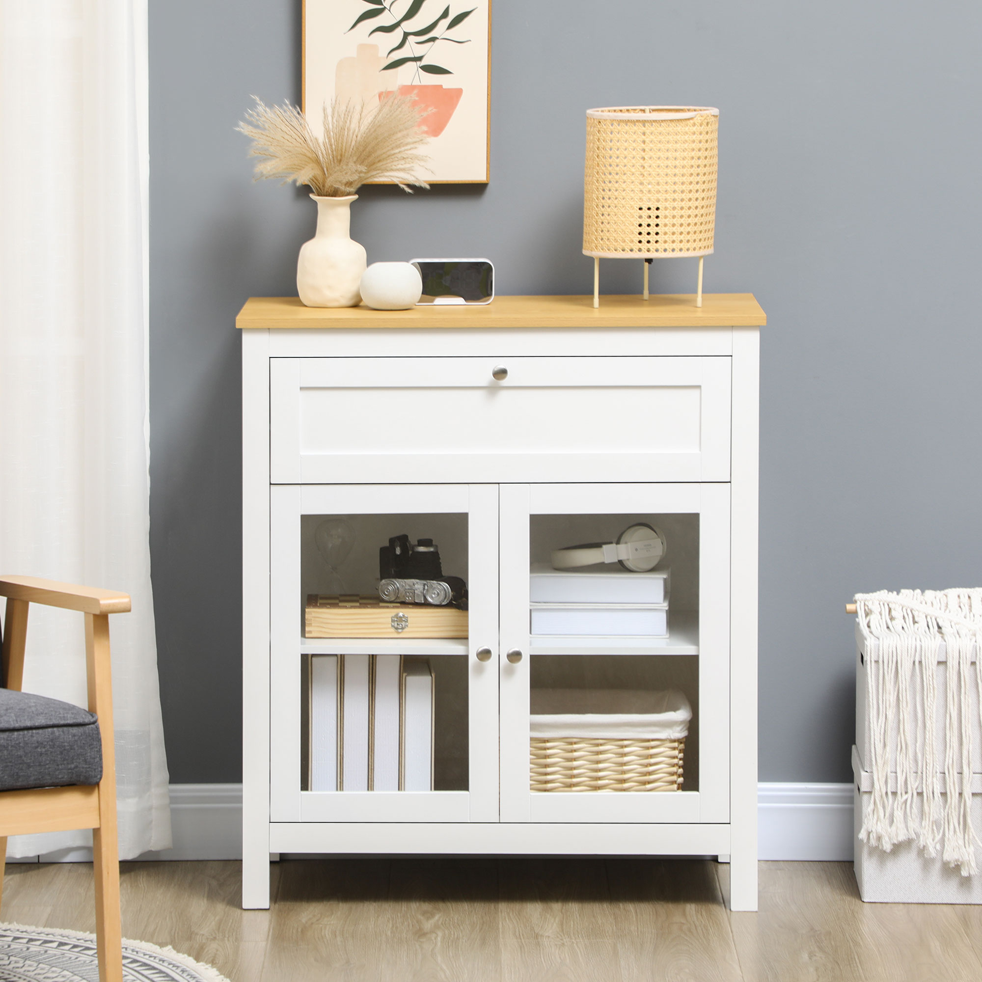Armario blanco con tapa de madera, puertas de cristal, cajón. Decorado con jarrón, lámpara, libros, cámara, cesta.