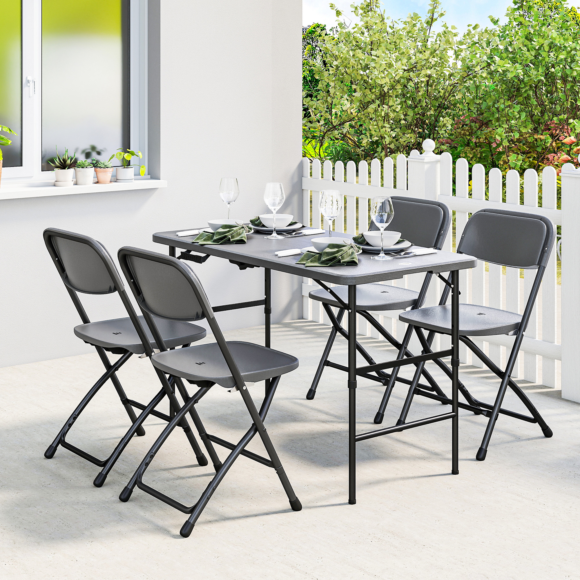 Cuatro sillas plegables grises rodean una mesa plegable gris puesta para una comida en un patio.