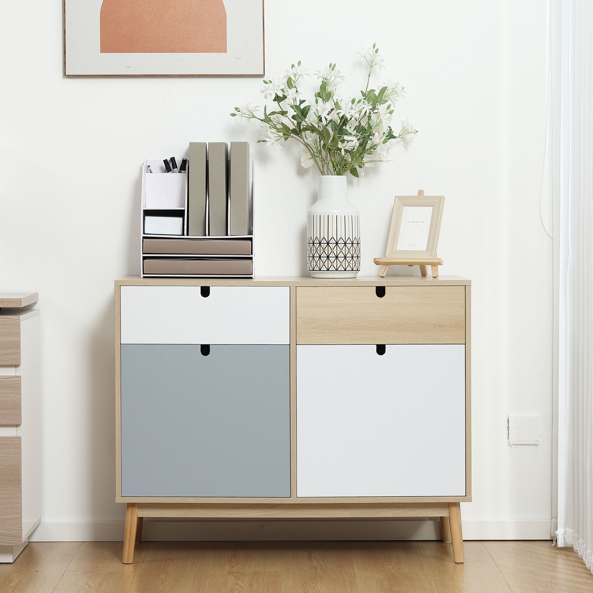 Un mueble de madera con cuatro cajones: dos blancos, uno gris y uno de madera.