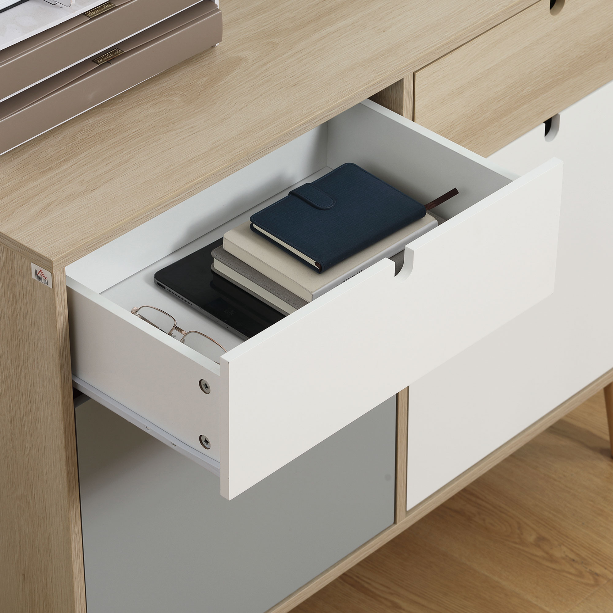 Un mueble de cajón abierto con libros, cuaderno y gafas dentro.