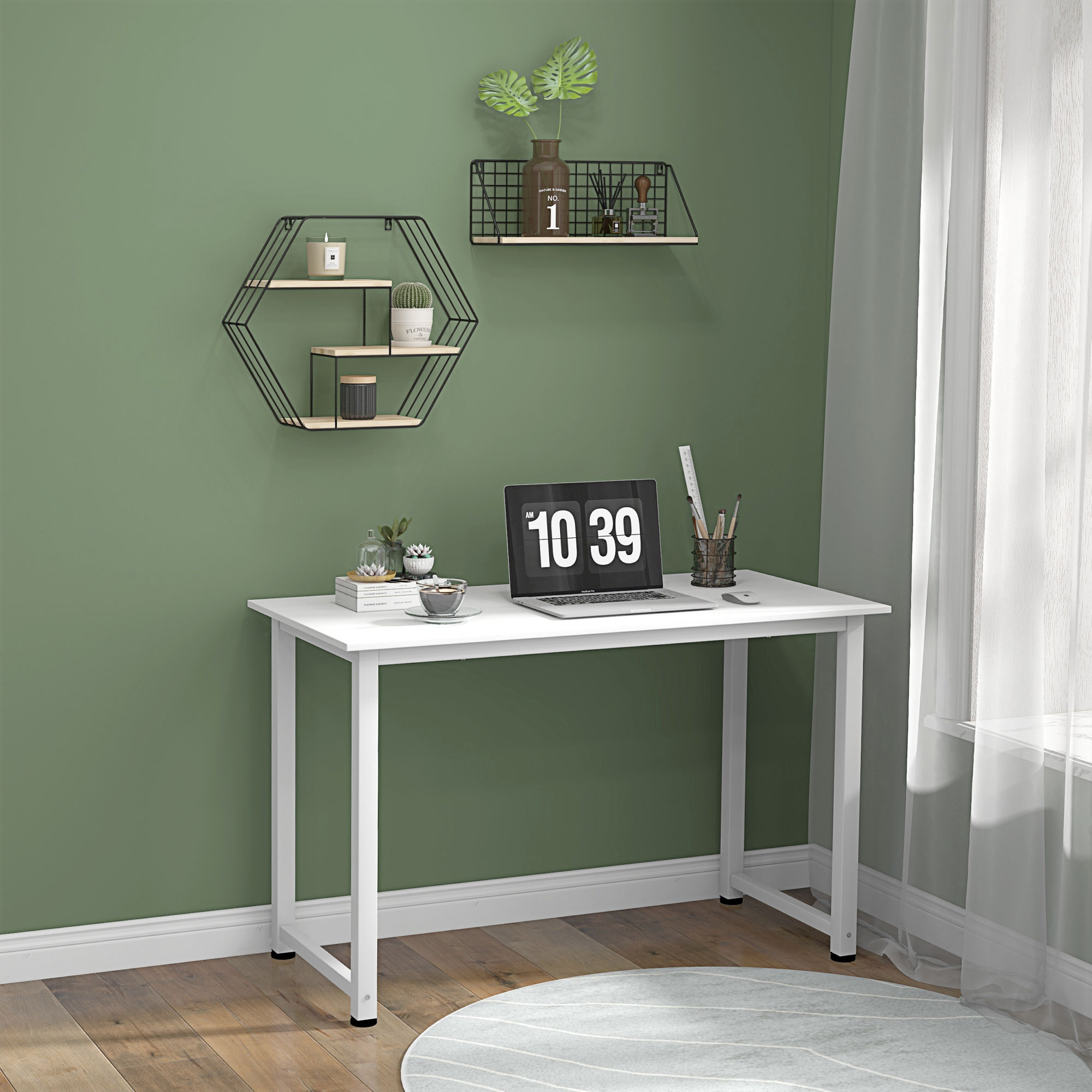 Un escritorio blanco con laptop, taza y decoración contra una pared verde.