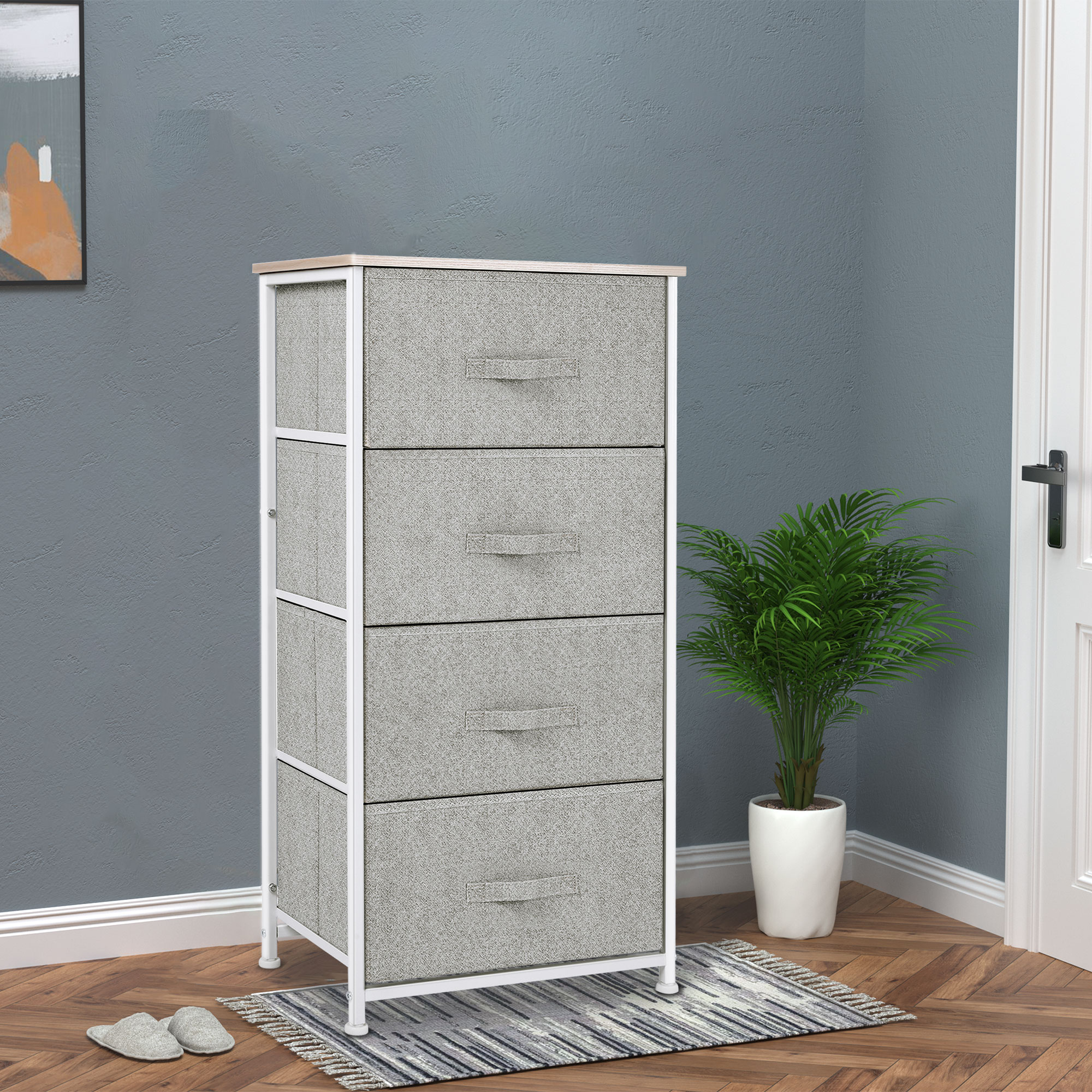 Cómoda de tela gris con cuatro cajones, tapa de madera, planta en maceta al lado.