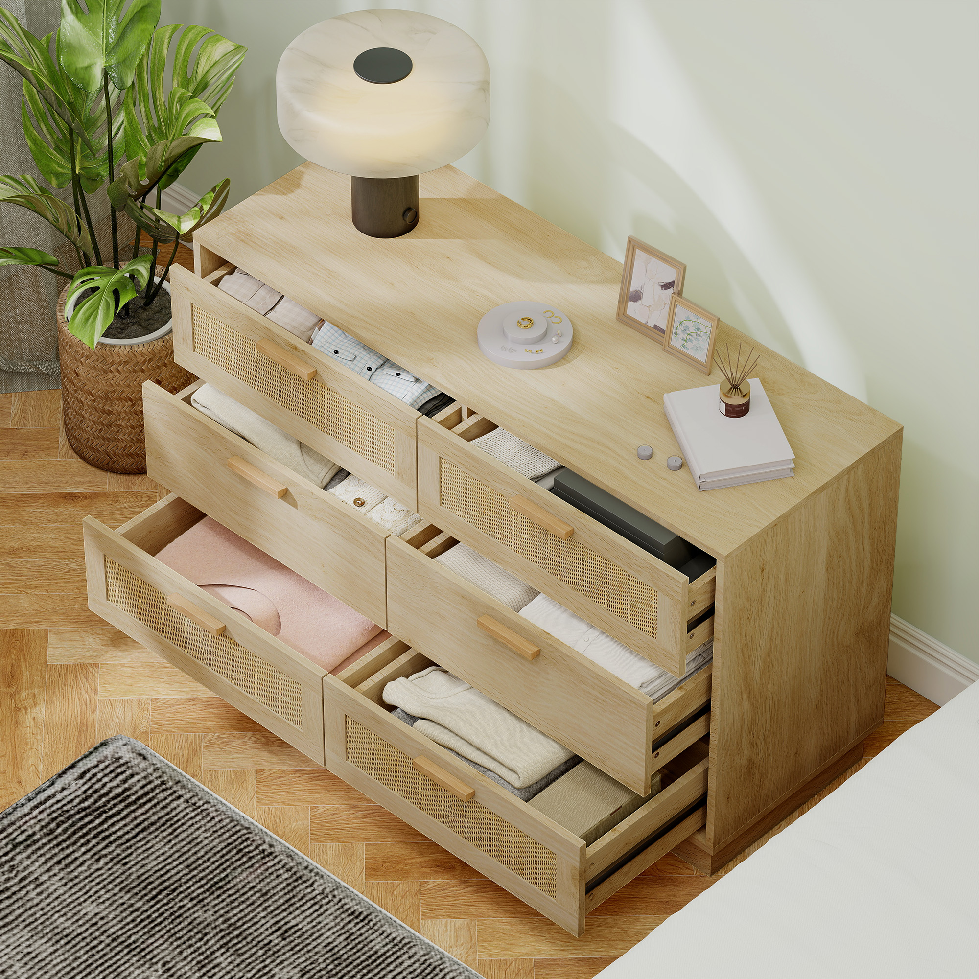 Cómoda de madera con cajones abiertos llenos de ropa, lámpara y plantas.