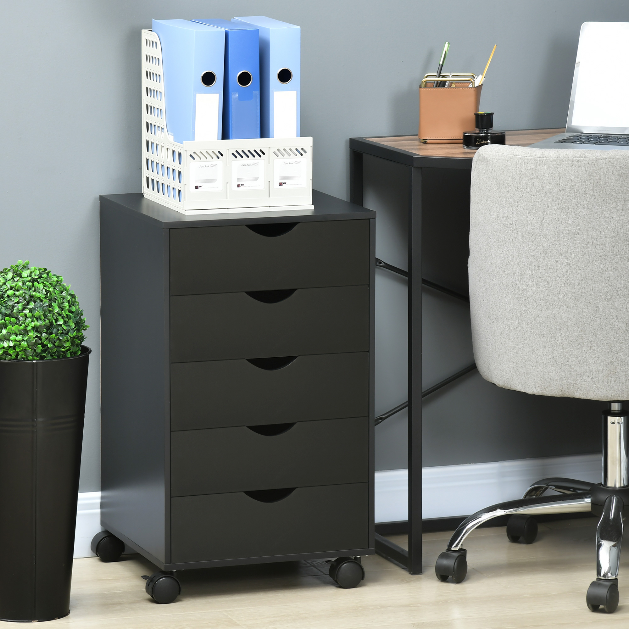 Cajonera negra con archivadores, escritorio y silla en una oficina.