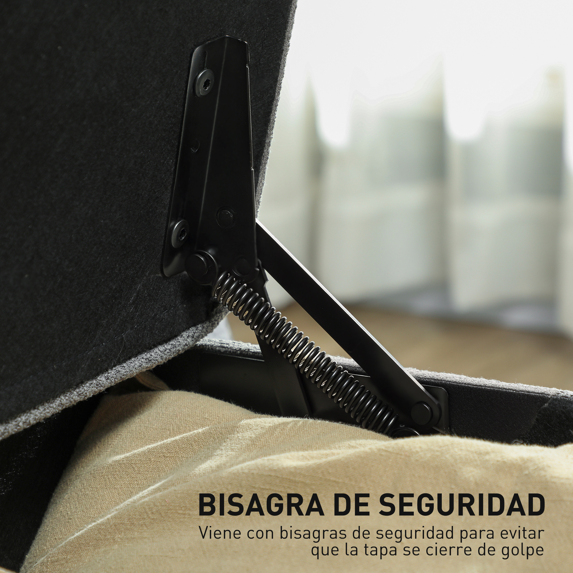 Primer plano de una bisagra negra con resorte en un mueble de tela gris.