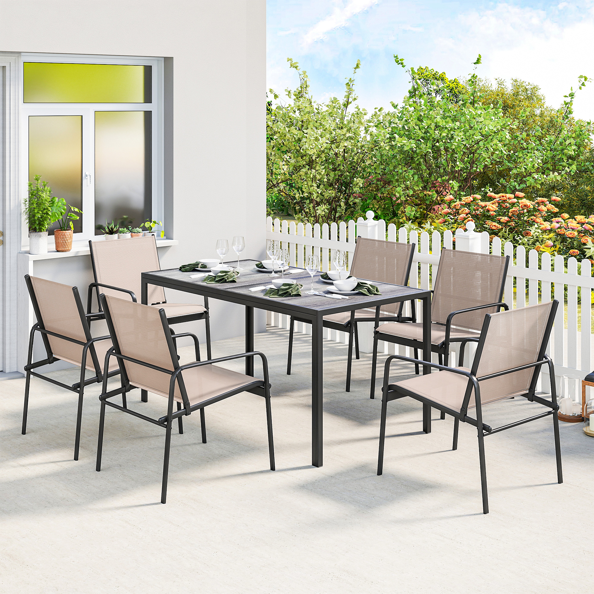 Una mesa de comedor con seis sillas en un patio, con flores y arbustos al fondo.