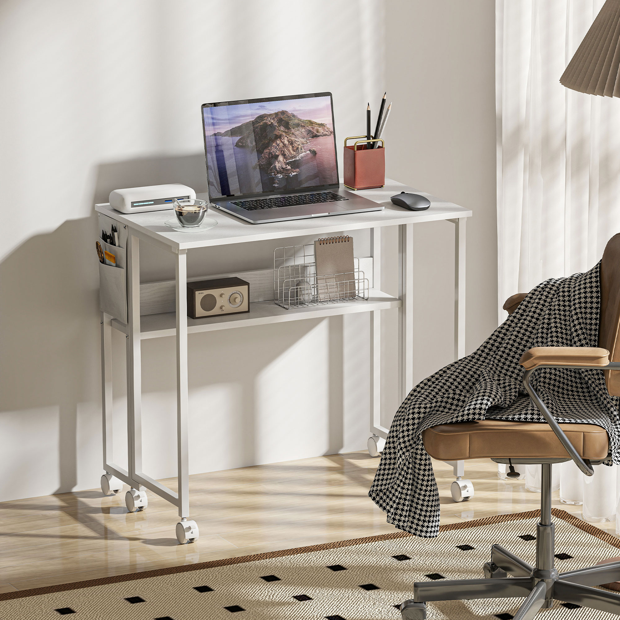 Un escritorio blanco con portátil, ratón, café y radio. Una silla marrón con manta.