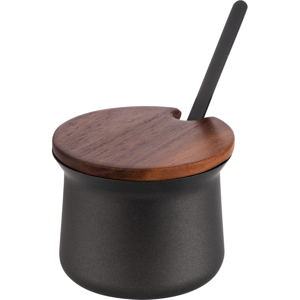 Ein schwarzer Behälter mit Holzdeckel und schwarzem Löffel.