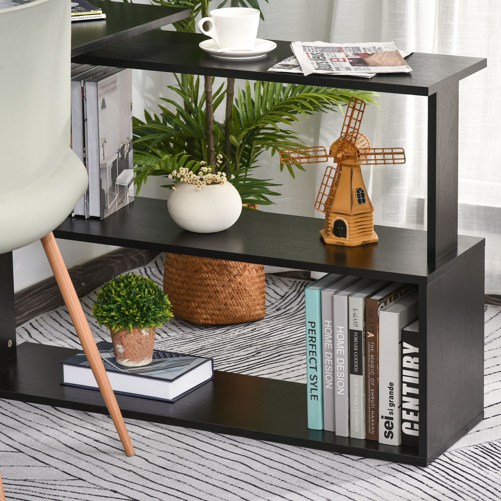 Un mueble de estanterías negro con libros, plantas, jarrón y decoración de molino.